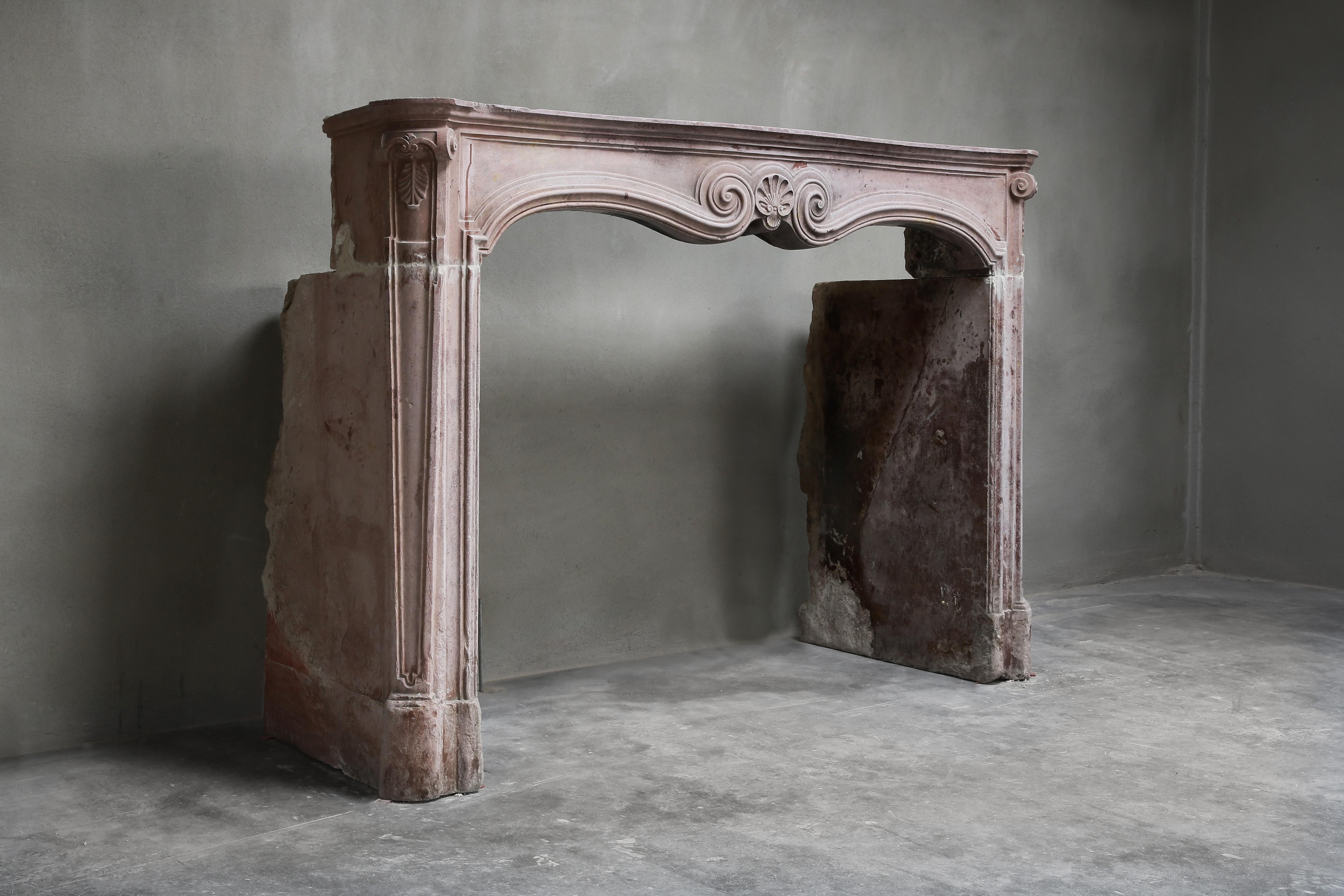A beautiful and rare antique marble mantelpiece in the style of Louis XV. This mantelpiece dates back to the 19th century and is of the marble stone 'Pierre de Vosges', a French marble. The fireplace has a beautiful ornament in the middle of the