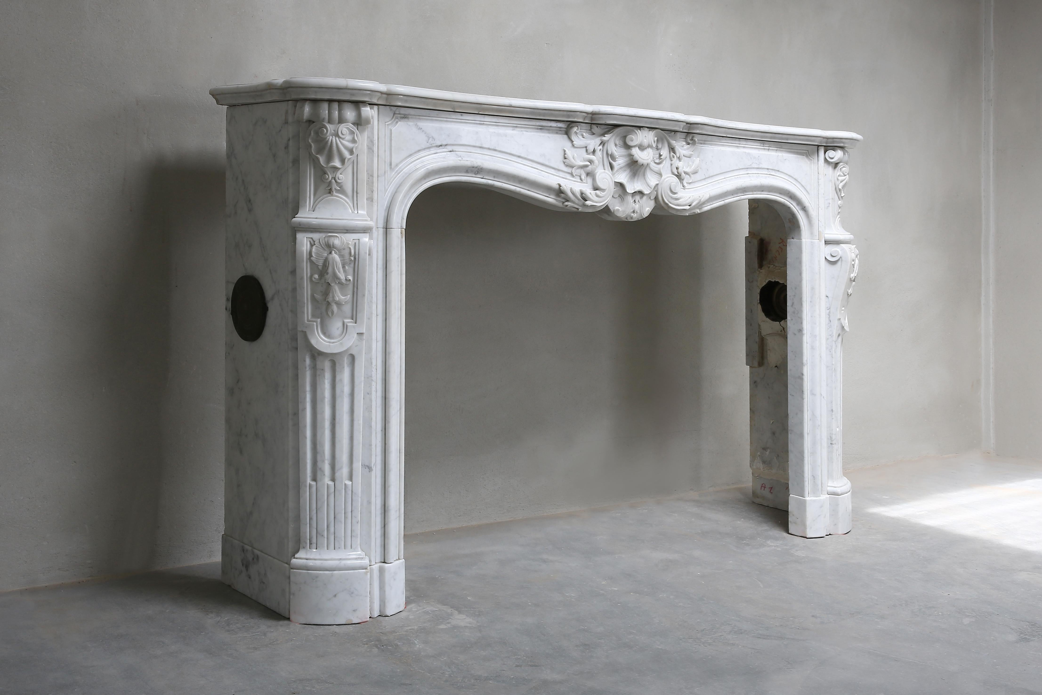 Beautiful Carrara marble fireplace from late 18th Century or early 19th century. 
A richly sculptured fireplace with decorations and a scallop in the middle and on the sides with various ornaments and flutes on the legs.