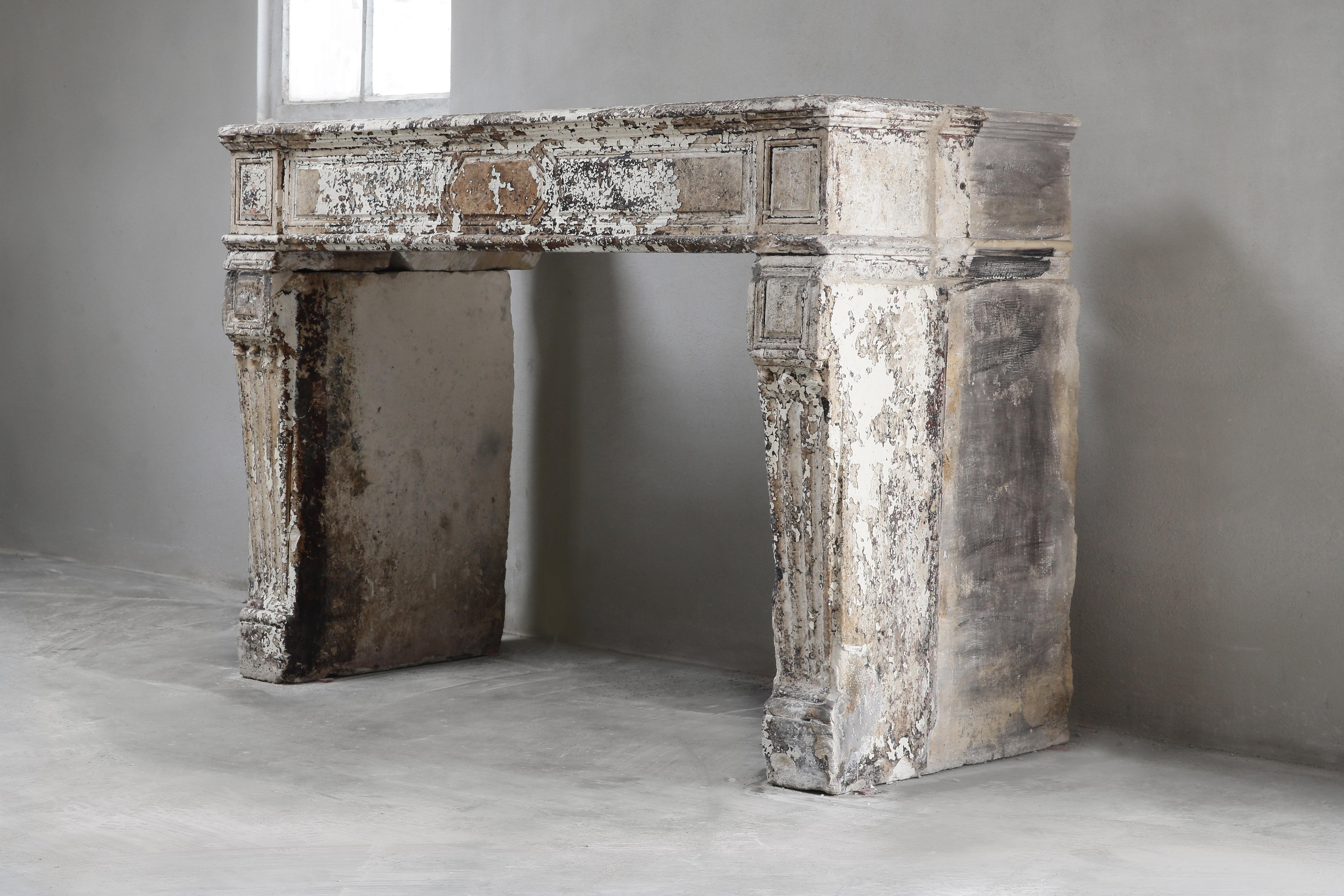 A very special antique French fireplace made of limestone. A fireplace with history! The old paint and imperfections gives this chimney an historical appearance. This antique fireplace dates back to the 19th century and is in the style of Louis XVI.