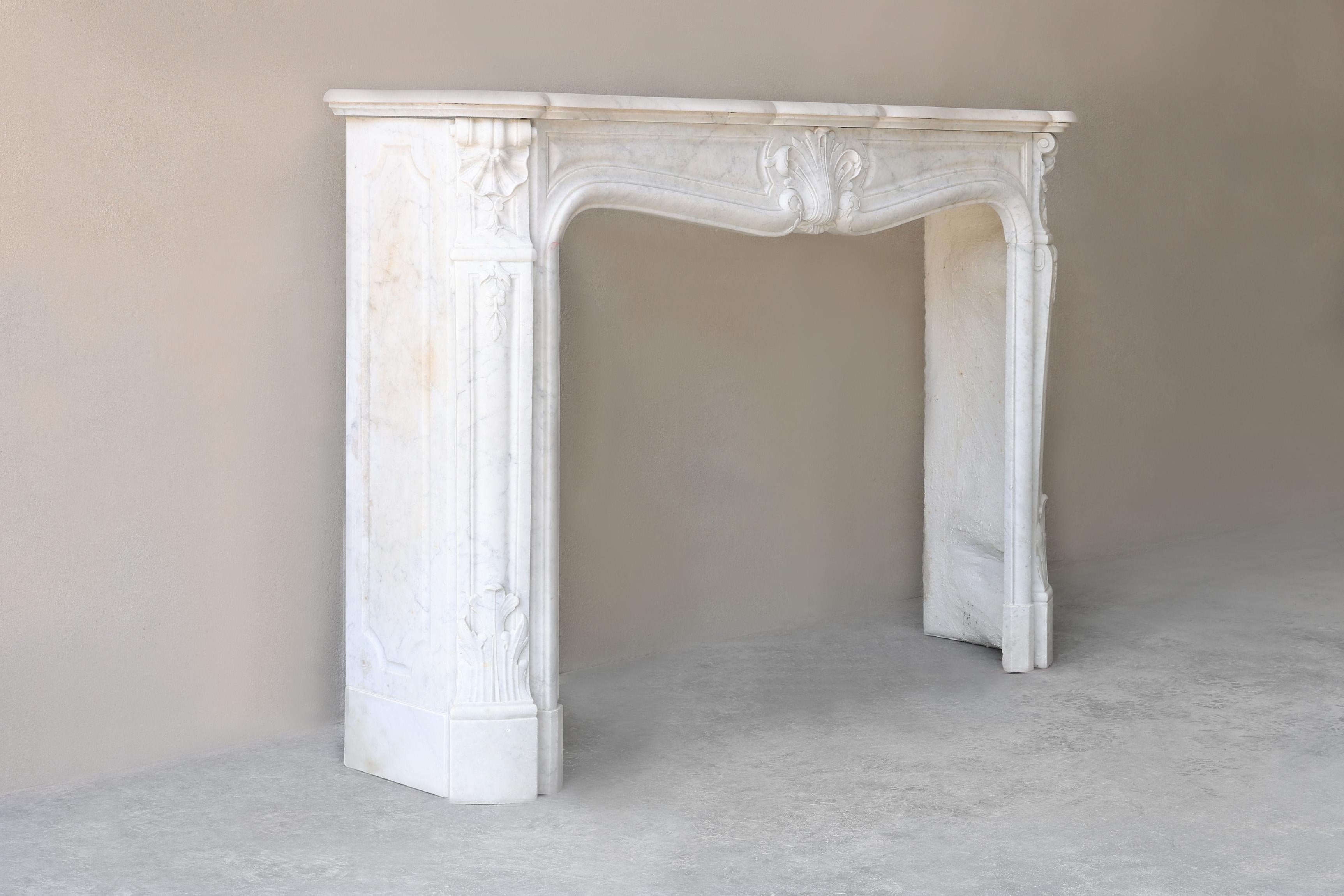 This rare 19th century Louis XV mantelpiece is crafted with finesse from fine Carrara marble. The elegant rococo lines, graceful shell motifs and refined details exude French grandeur. A beautiful compact fireplace with an elegant appearance,