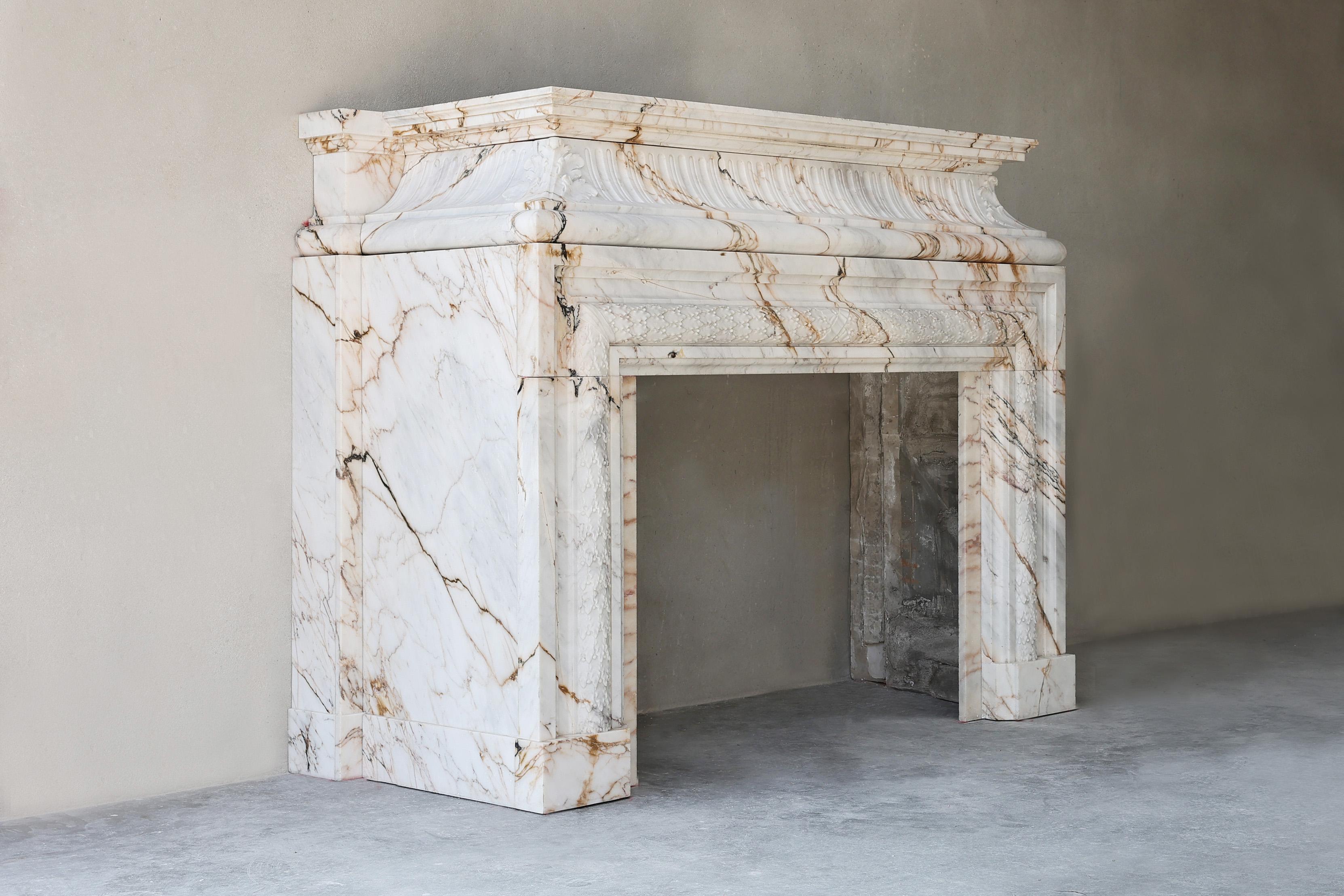 Une cheminée monumentale en marbre de Paonazzo du XIXe siècle, de style Louis XIV, délicieusement sculptée avec des détails d'Acroterion. Cette cheminée ancienne, en luxueux marbre Paonnozetto, évoque l'opulence du Château de Versailles. Les