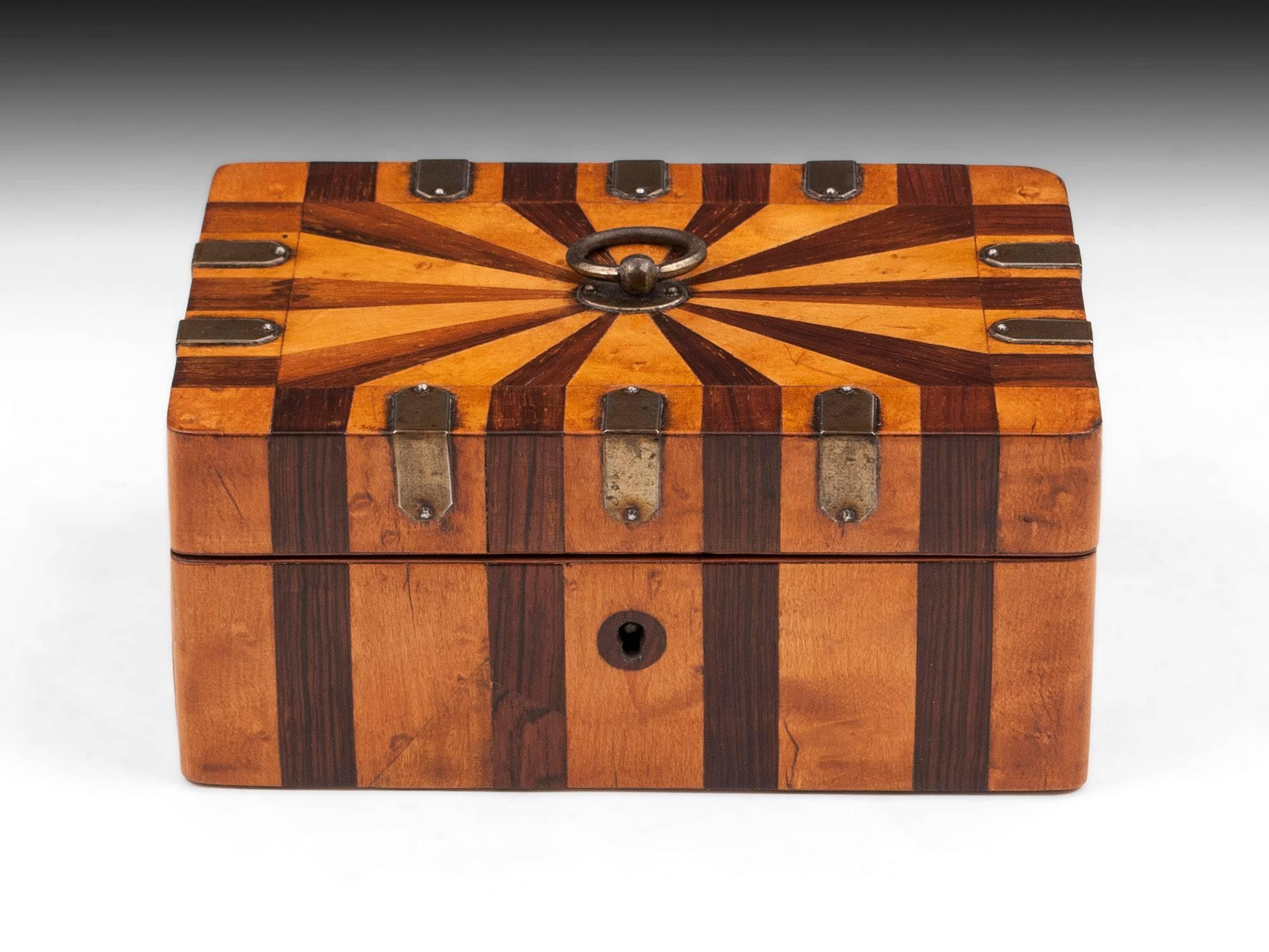 Palais Royal sewing box with mahogany and maple striped design with cut steel corner brackets and sturdy ring handle. 

The interior of this palais royal sewing box features a padded removable tool tray fitted with Various gilt tools including a