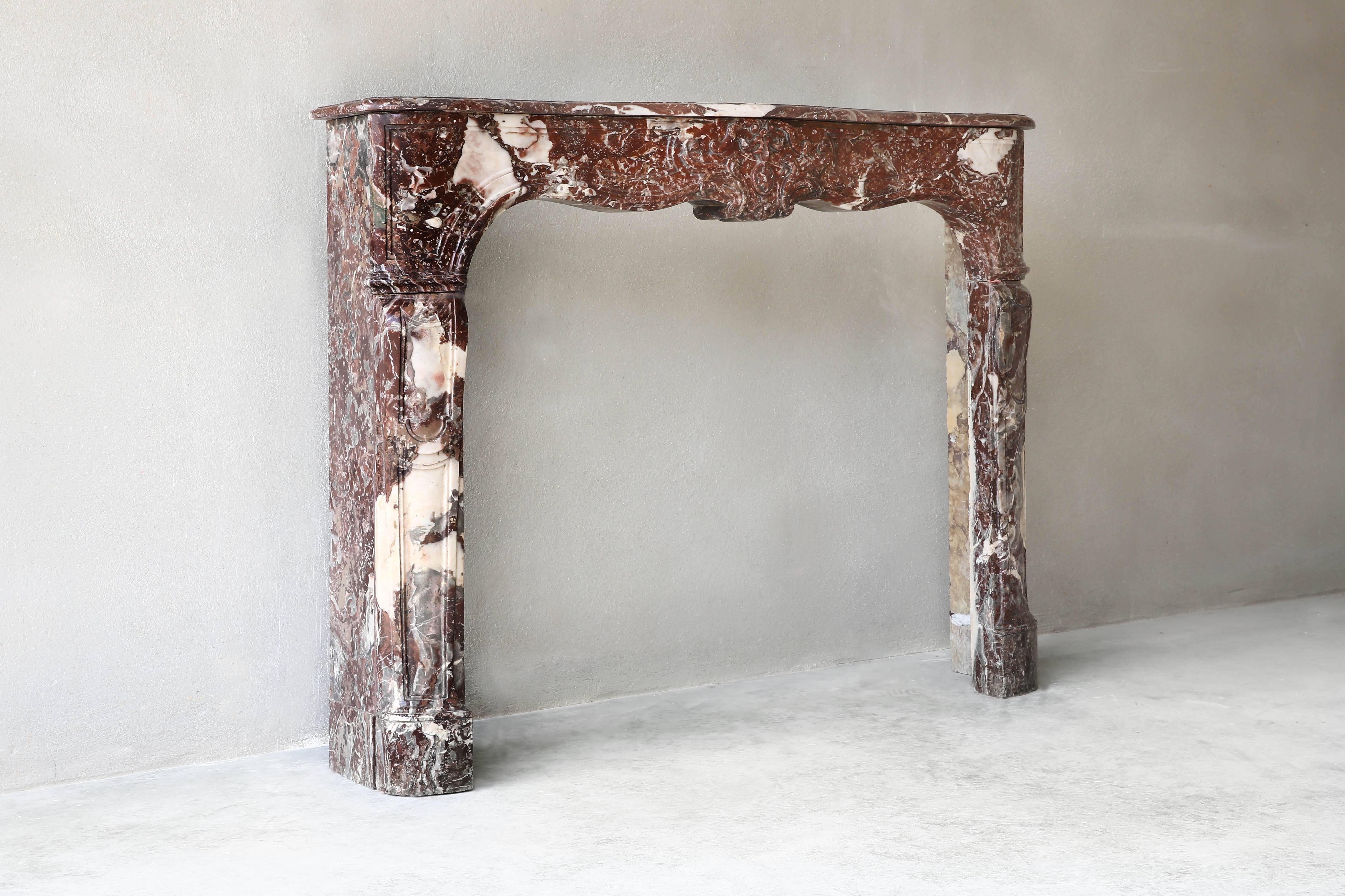 Charming antique marble fireplace of Griotte rouge de Belgique. This fireplace is from the 18th century in the style of Louis XV.
