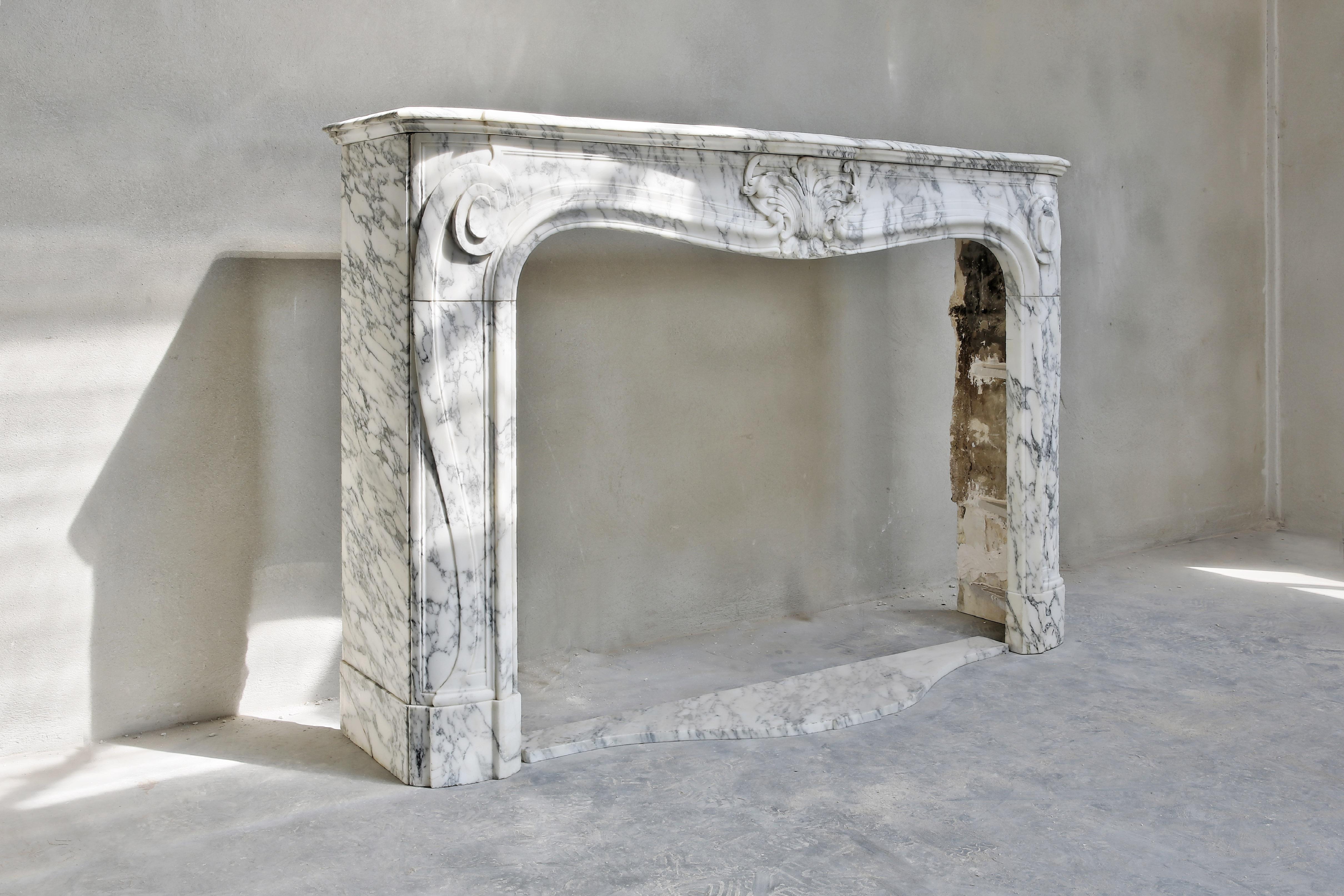 Very special antique marble fireplace from the Arabescato marble from Italy. This white mantelpiece with gray veins is in the typical Louis XV style. One coquille in the middle and different ornaments on the legs. Also the moulure is very nice at