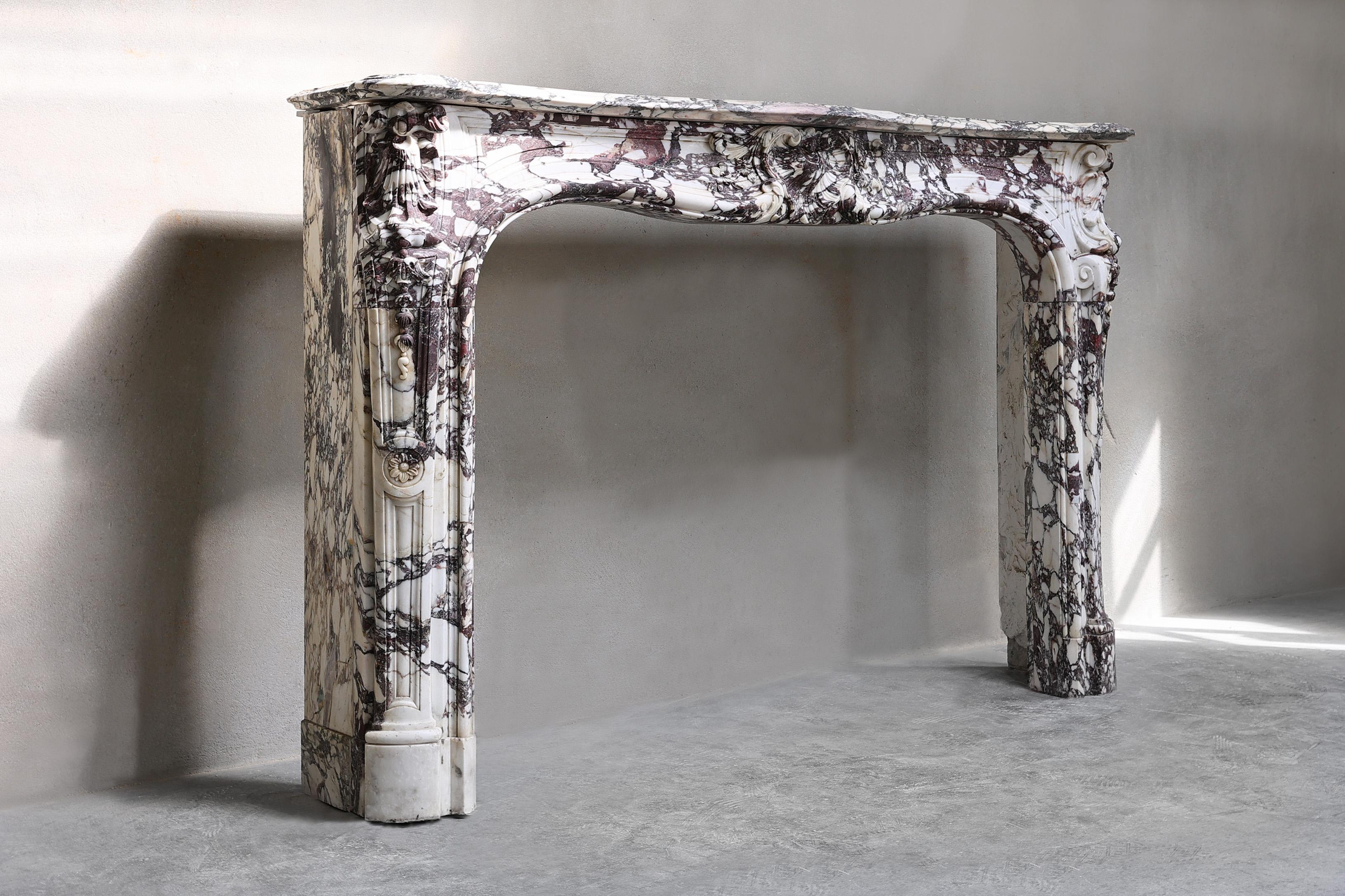 Beautiful colorful antique fireplace of the exclusive marble type Breccia Violetta. This fireplace dates from the 18th century and is in the style of Louis XV. A special mantle with a chic look and warm color nuance. This fireplace is equipped with