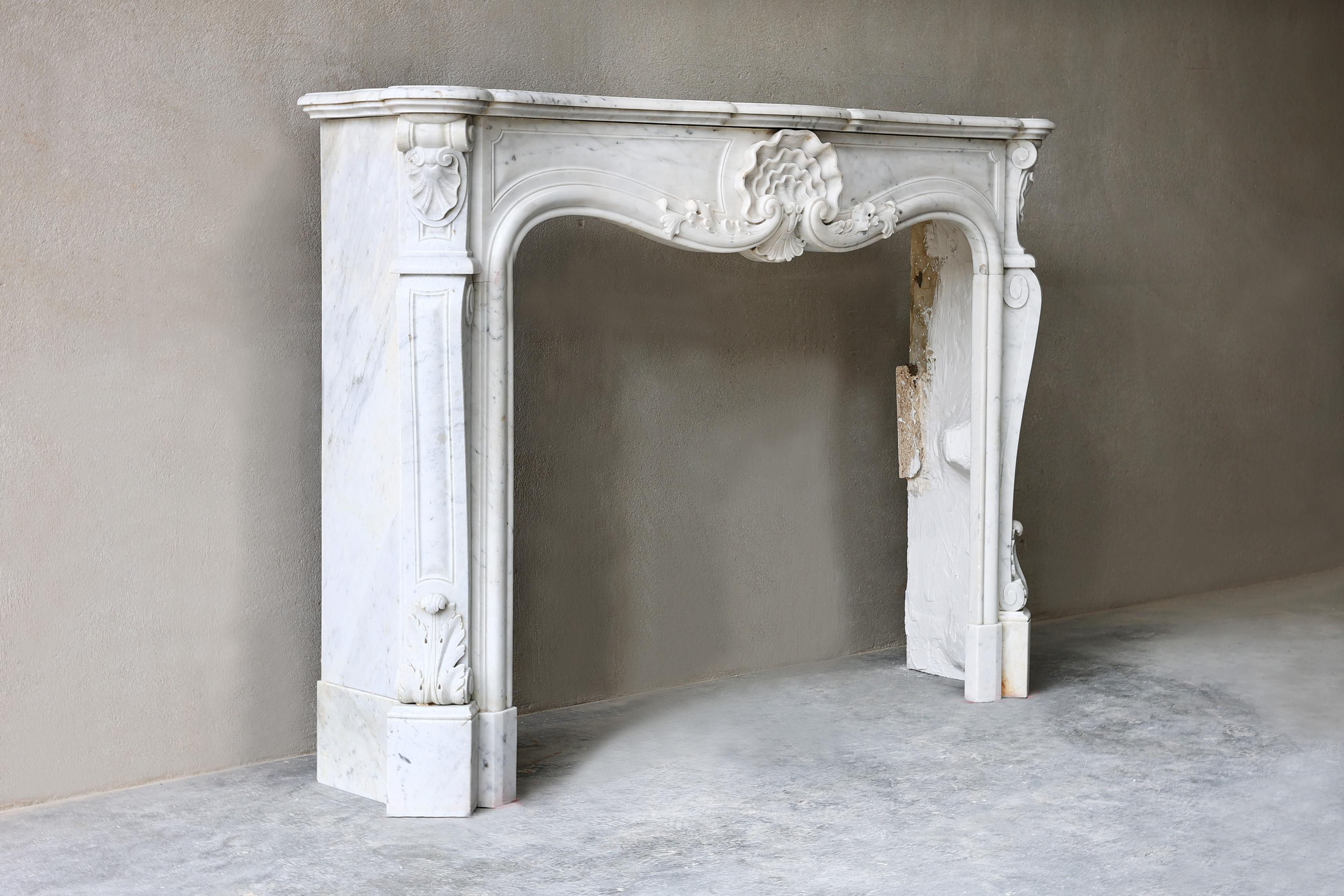 Beautiful antique French Carrara marble fireplace from the 19th century in the style of Louis XV. A fireplace with a beautiful rosette in the middle of the front part and graceful legs with various ornaments. A beautiful fireplace that is elegant