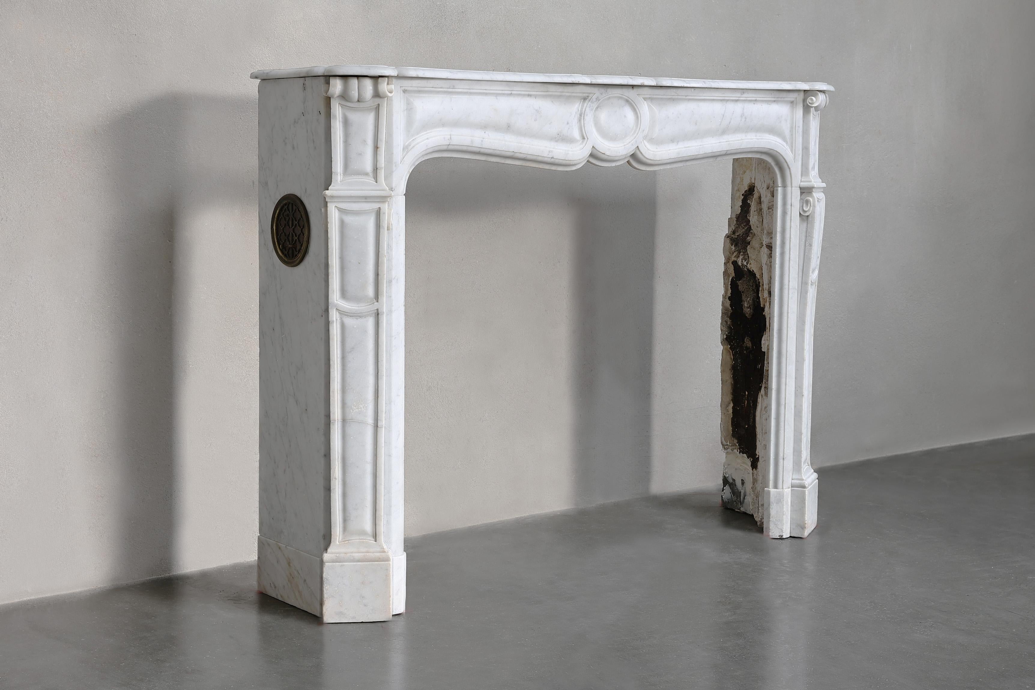 Beautiful compact antique mantelpiece made of Carrara marble from the 19th century! This graceful mantle is in Pompadour style, characterized by the round ornament in the center of the front part.