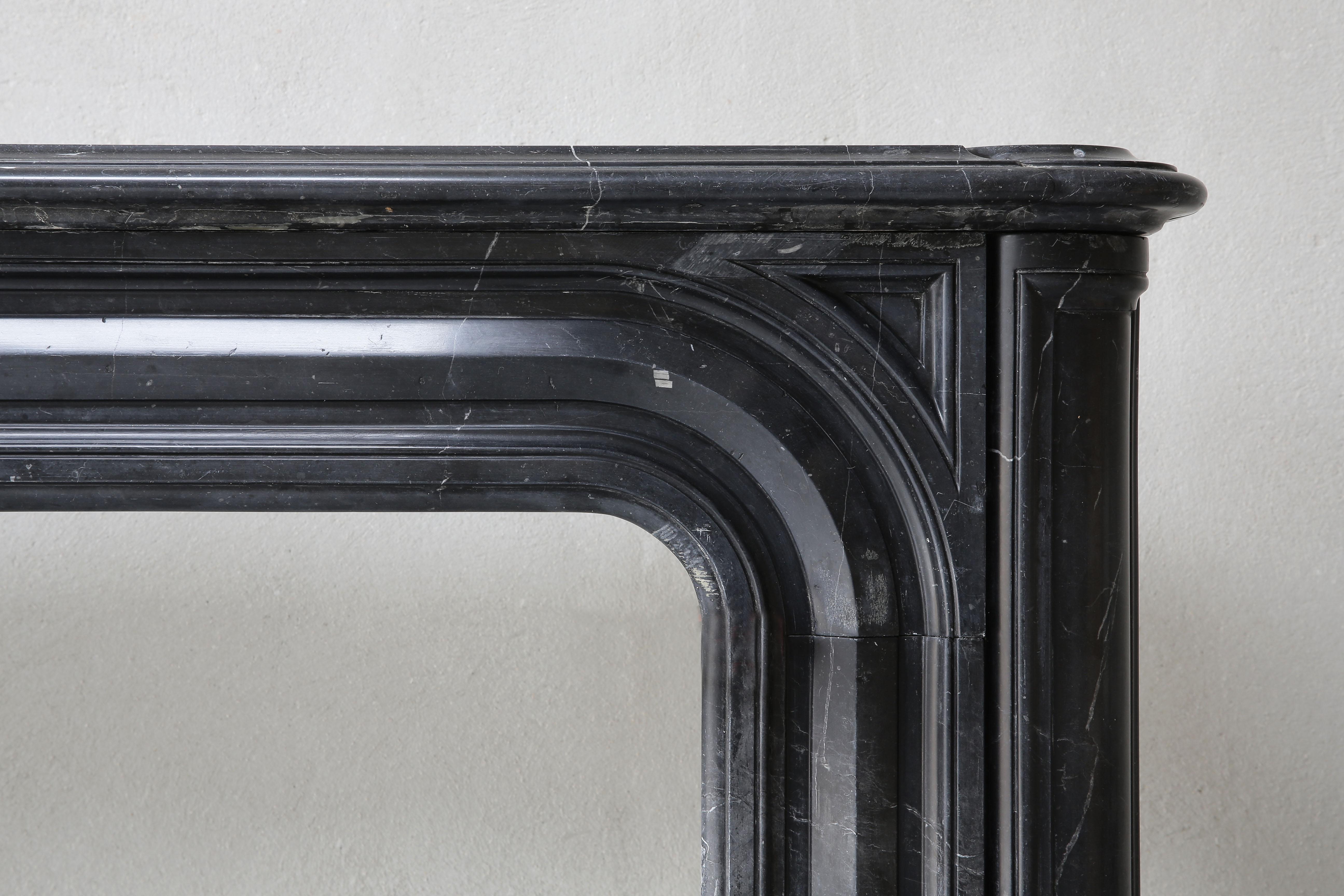 Beautiful antique marble fireplace from Nero Marquina marble. This type of marble comes from the North of Spain. In this marble type you see white veins, in contrast to Noir de Mazy marble that is uniformly black in color. This mantelpiece dates