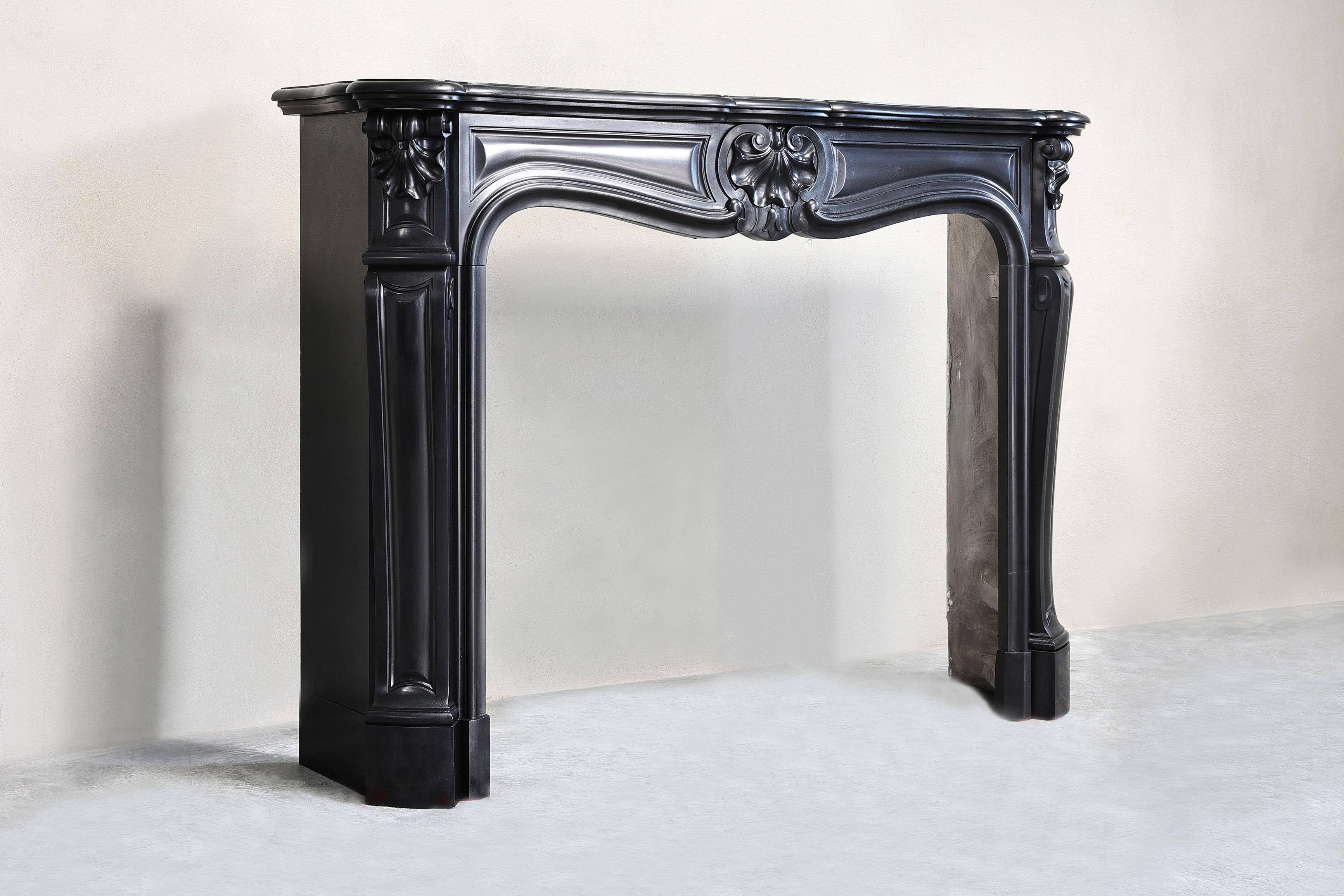 Beautiful antique fireplace of the rare type of Noir de Mazy marble from the 19th century in the style of Louis XV. This mantel has a scallop in the center of the front section and also two scallops on the legs! A very chic mantelpiece with a warm