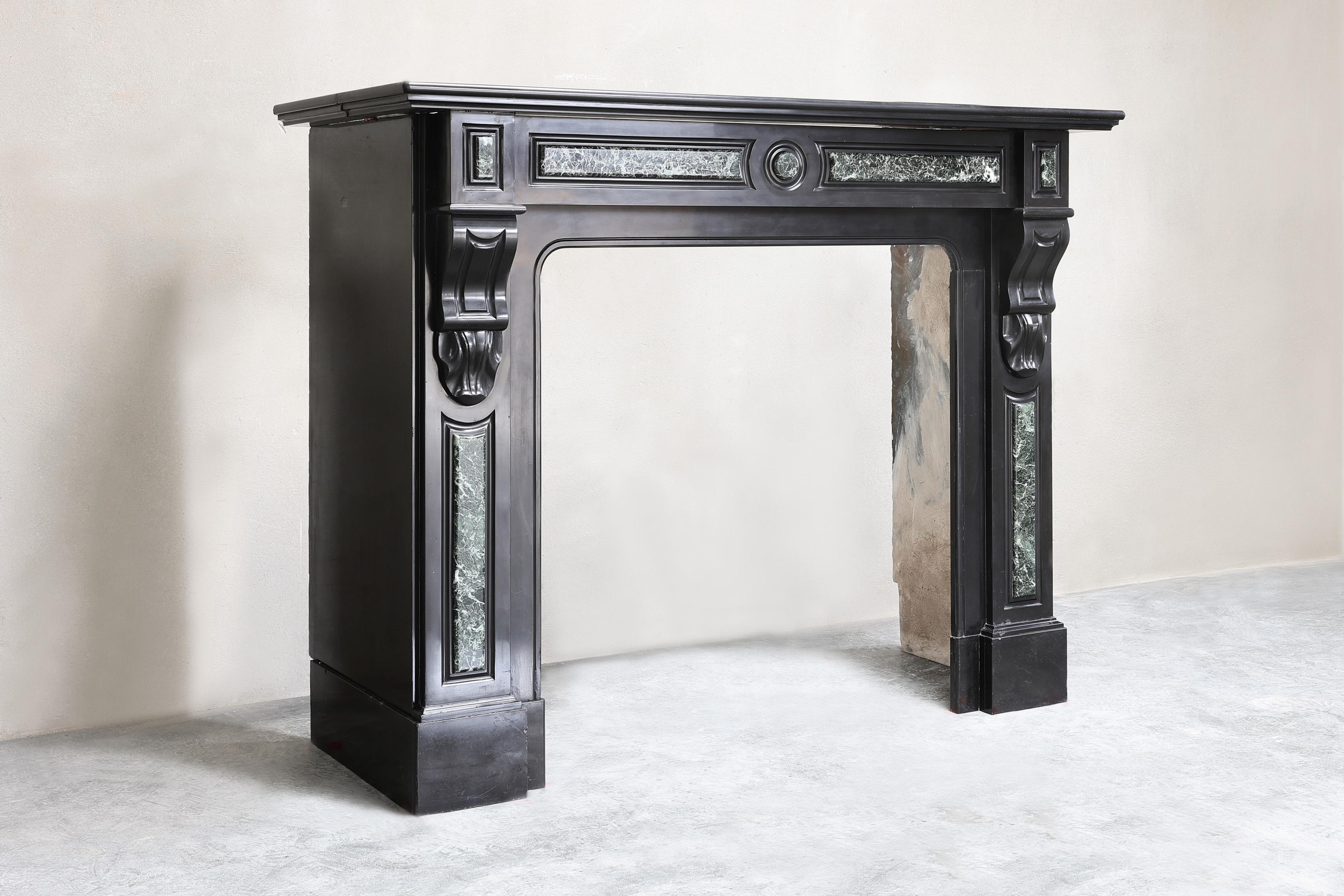 Beautiful antique mantelpiece made of Noir de Mazy marble combined with green marble. This mantle dates from the 19th century and is in the style of Louis XVI. A compact mantelpiece due to its size that can be used in many interiors.