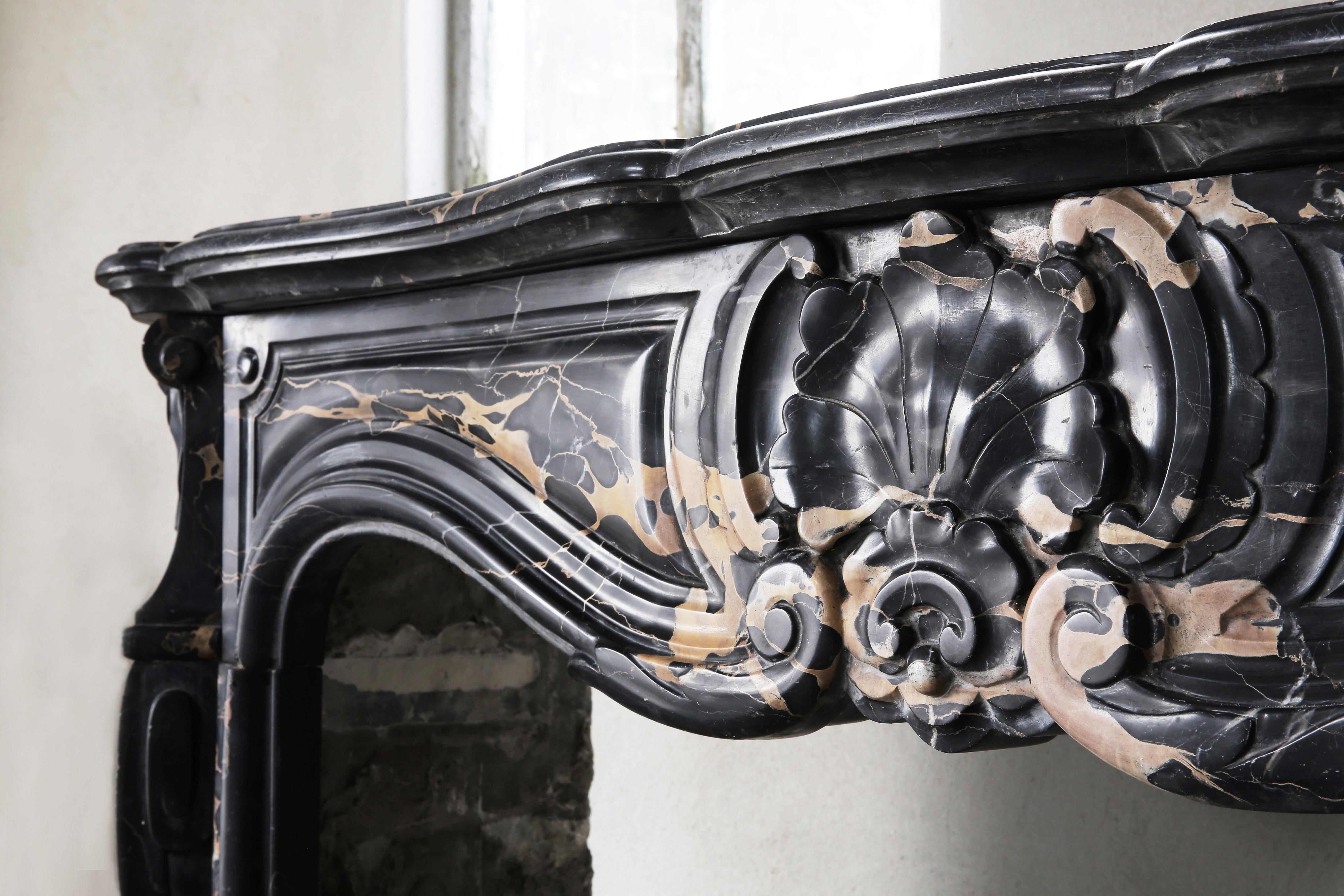 A rare antique marble fireplace from ancient Portoro marble from Tuscany. Portoro marble is one of the most elegant Italian marbles. The black background with golden veins ensures luxury and exclusivity. The chimney is in Louis XV style and dates
