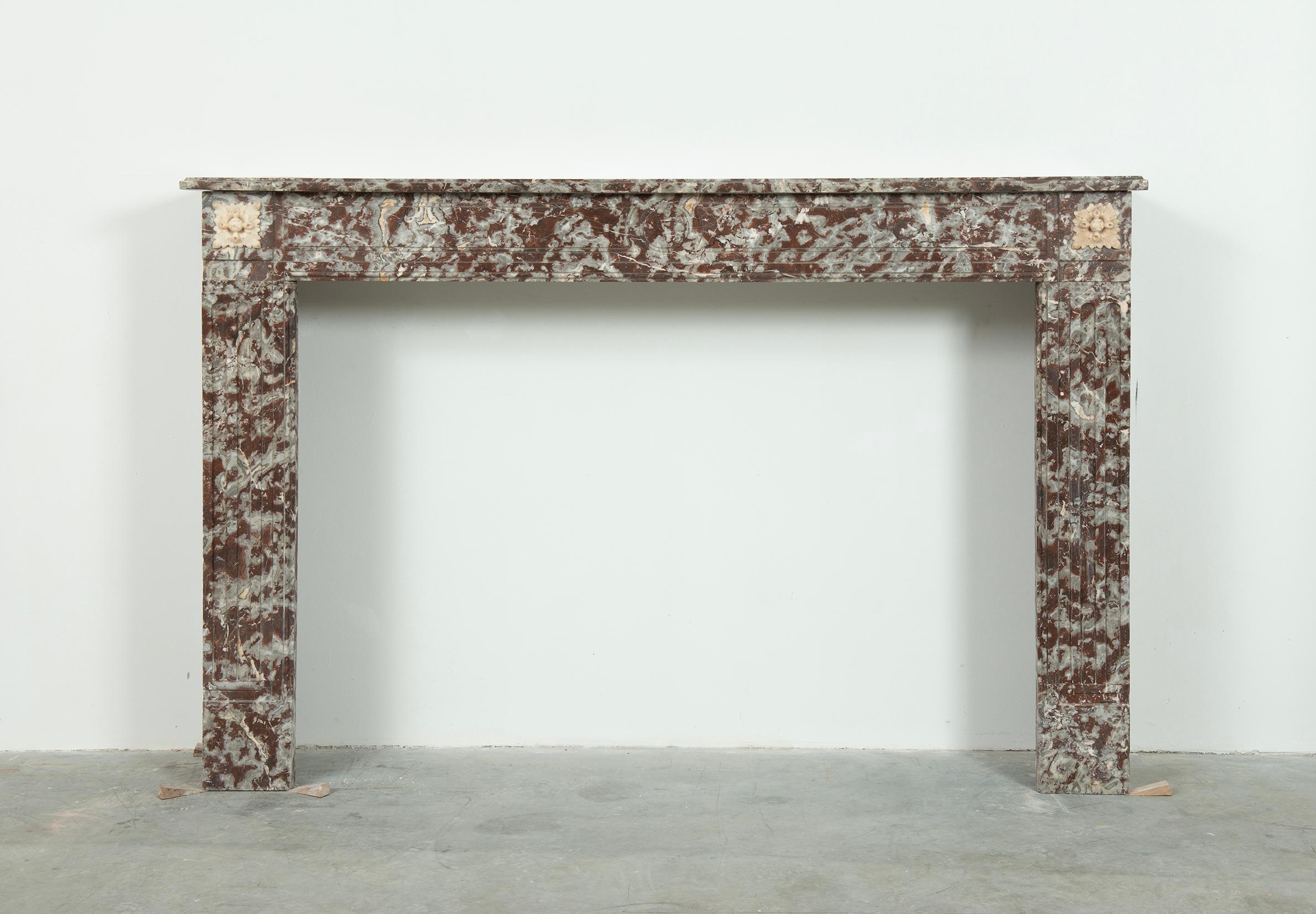 Antique Marble Louis XVI Fireplace Mantel.

A nice and large Louis XVI in red marble with Carrara white marble floral details.

The rectangular topshelf has a nice edge profile and sits above a straight paneled frieze with a centered disk and floral