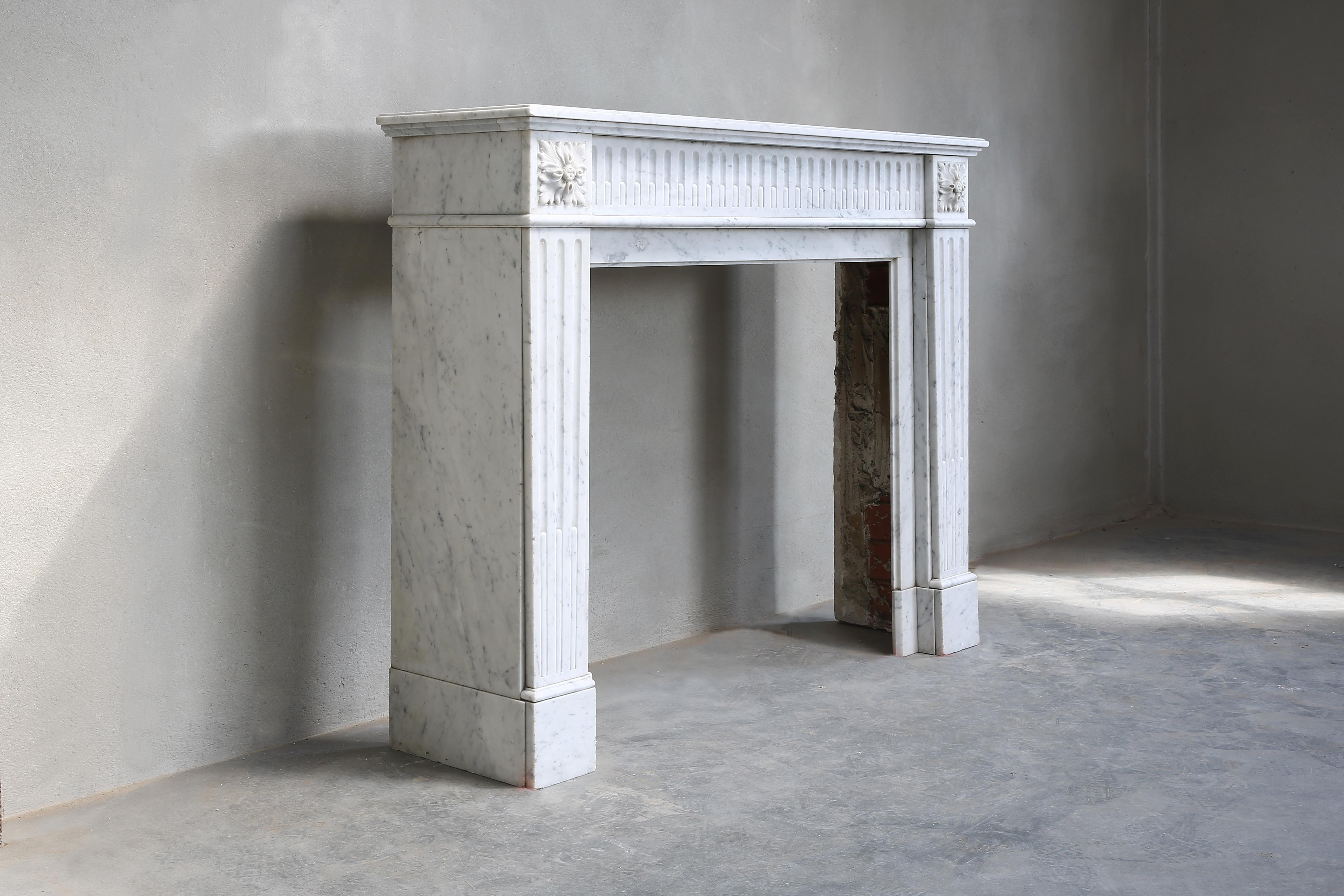 Beautiful antique fireplace of Carrara marble from the 19th century. This fireplace is from Paris and is in the style of Louis XVI. The fireplace is richly decorated with flutes in the front part and on the legs. A chic model that will fit perfect