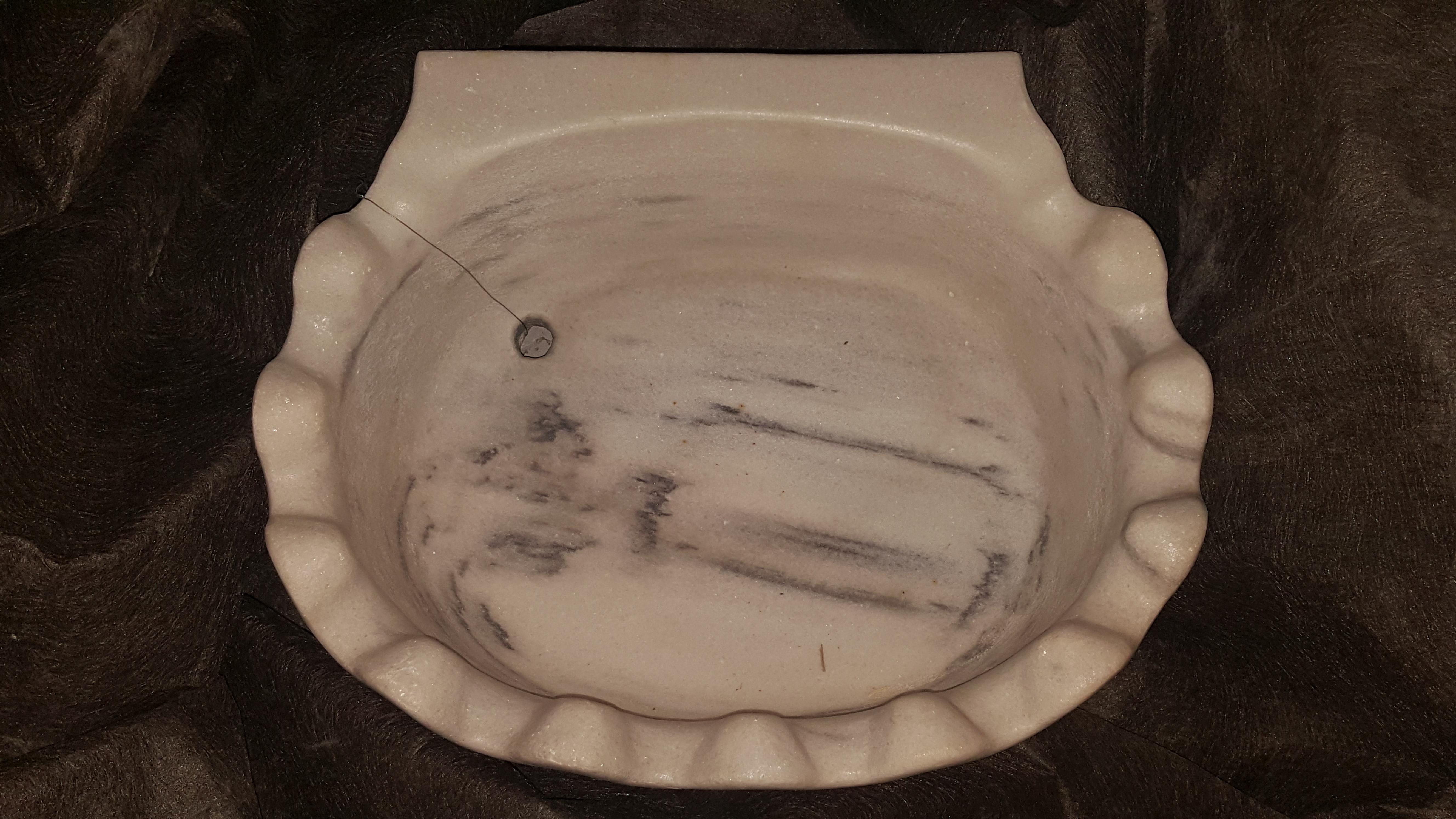 Antique marble sink with a scalloped sea shell design.