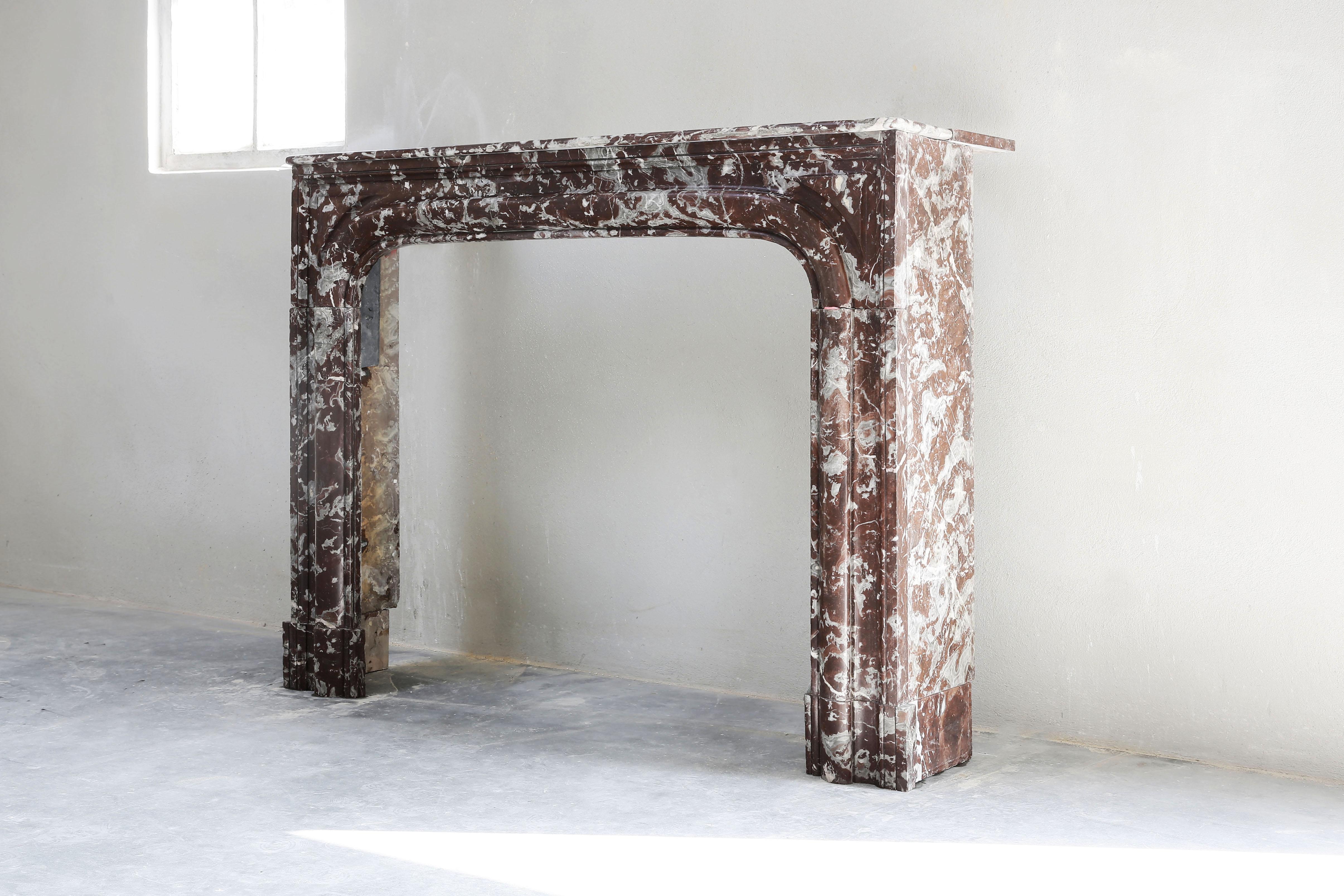 A unique marble fireplace from the marble variety Griotte Rouge de Belgique. The color of the fireplace is brown with white/gray veins, a warm mixture with color nuance! The antique fireplace dates back to the 19th century and is in Louis XIV style.