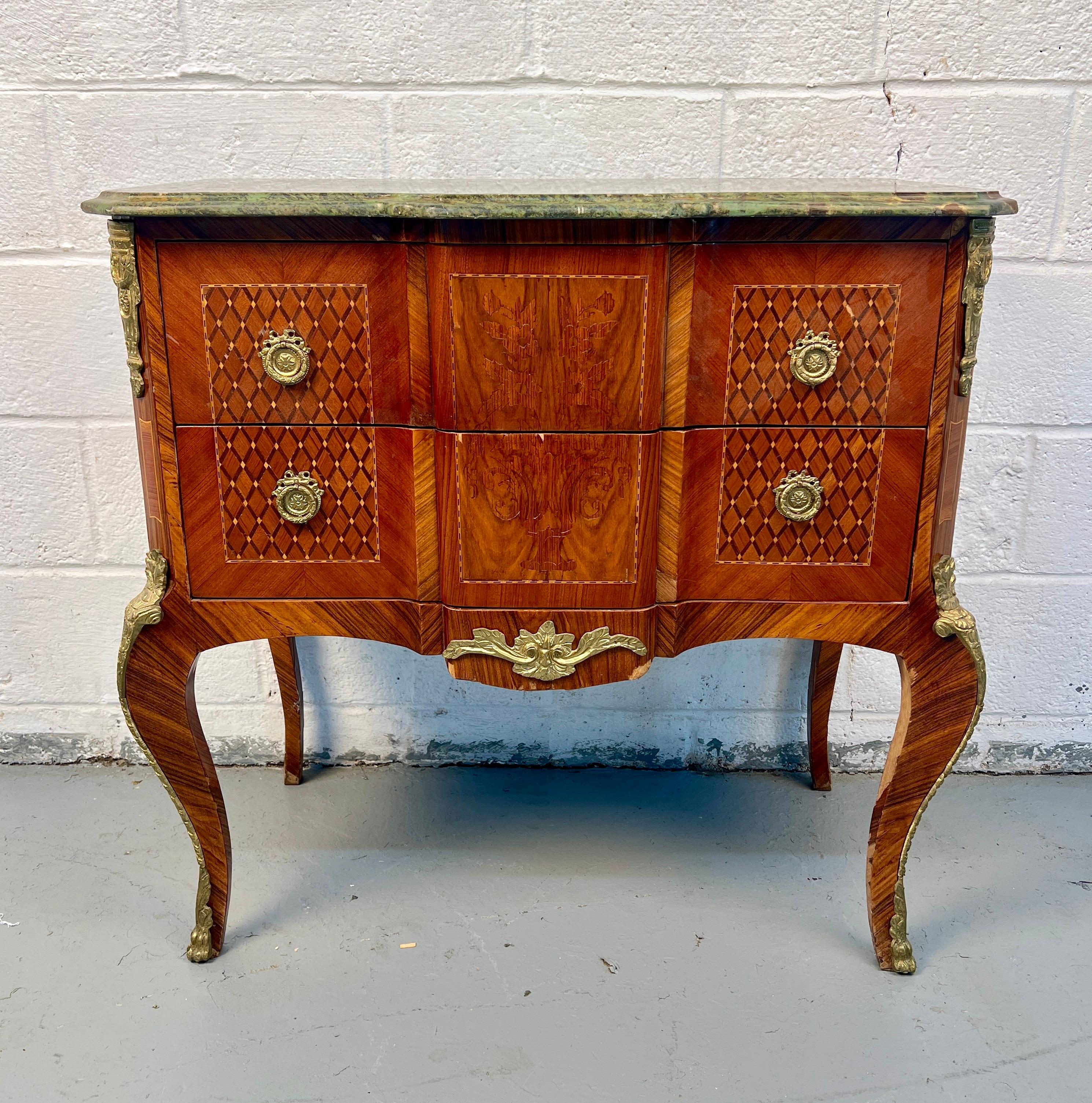 Elegante commode francese d'epoca in stile Luigi XV con una forma a bombe serpeggianti, un'intricata impiallacciatura di intarsio e un ricco piano in marmo verde. Caratterizzato da decorazioni in bronzo dorato e ormolu e da graziose gambe a