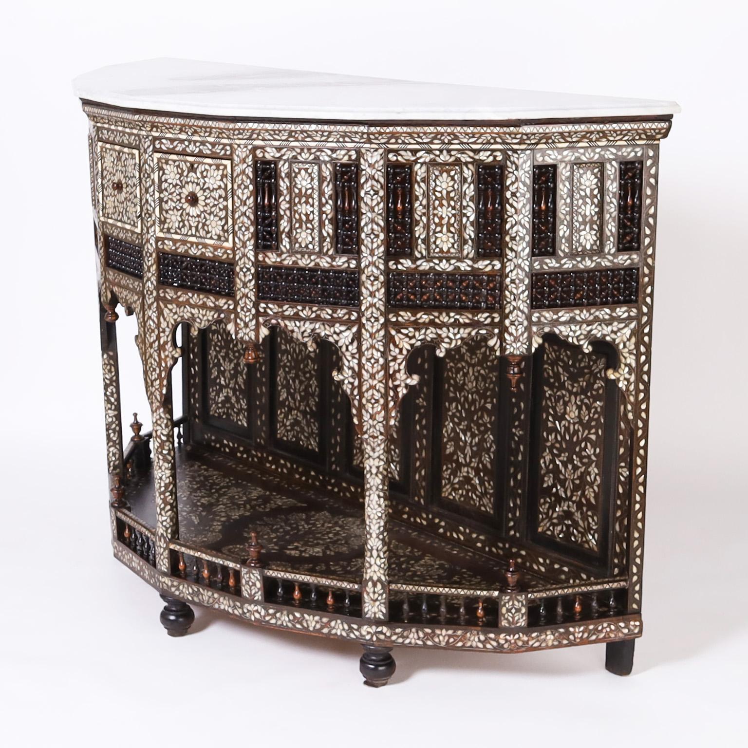 Impressive large scale antique Anglo Indian demi lune console with the original beveled white marble top over an architecturally interesting base crafted in mahogany featuring mother of pearl floral inlays throughout, two drawers, stick and ball