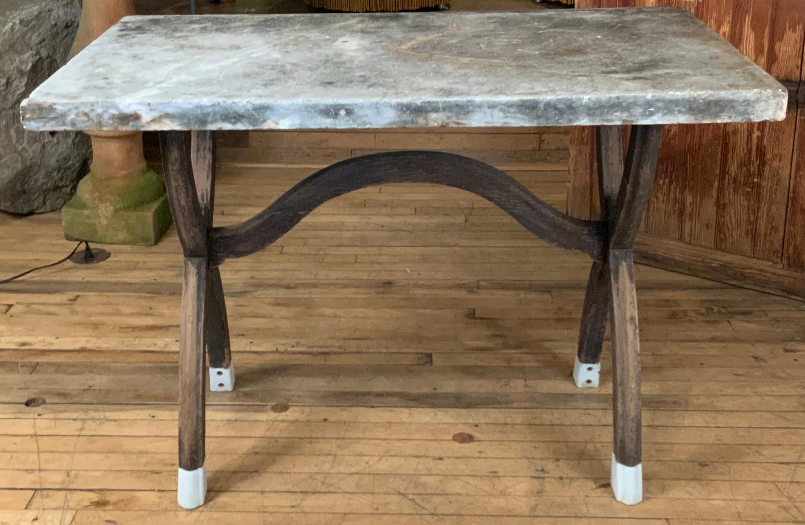A very nice early 20th century wood base table with a thick antique marble top and curved X base with charming enameled feet. Beautiful sculptural form, and a beautiful marble top. Perfect for console or center table, or casual cafe or dining.