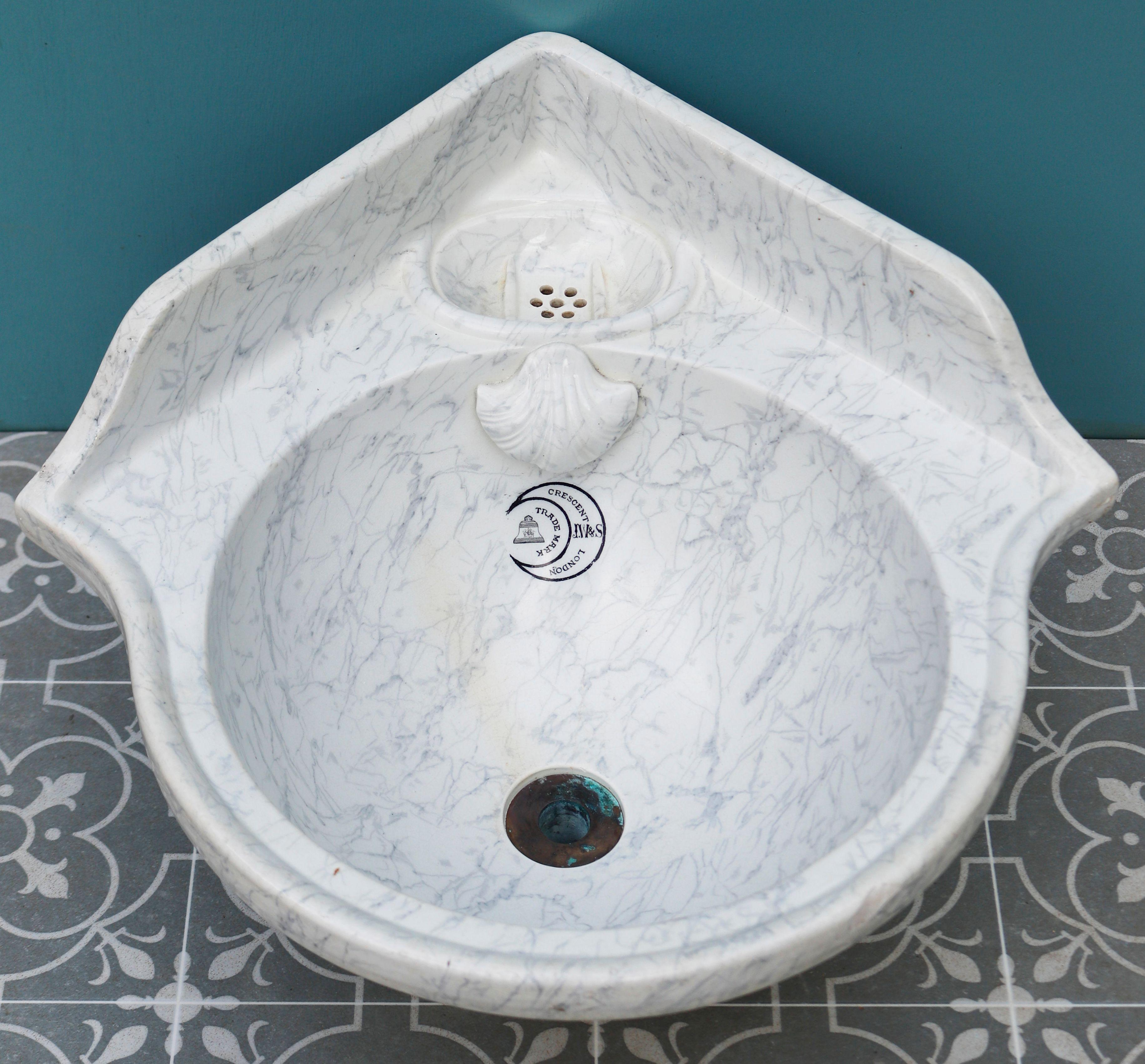 Small Antique Marbleised Sink. A small corner sink or basin with a simulated marble finish beneath the glaze. This has a shell shaped overflow cover and a soap dish with drain holes.
 
Additional dimensions
 
Overall height 30 cm
 
Front to back 51