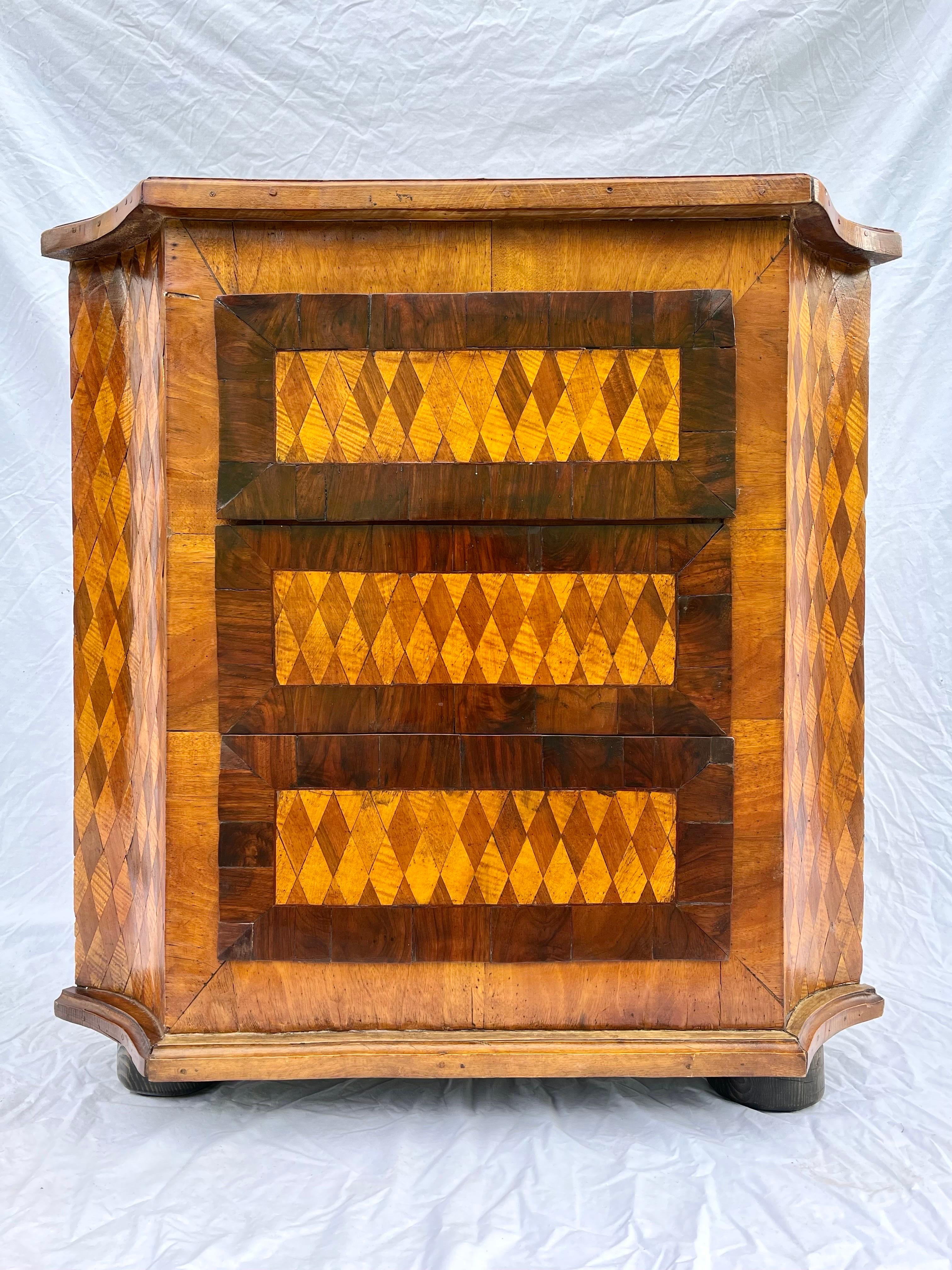 A gorgeous and dare I say modern antique diamond pattern marquetry inlaid three drawer corner cabinet. The all over, multi color, diamond pattern speaks to modern and contemporary interiors while the wood work and design are antique in origin. This