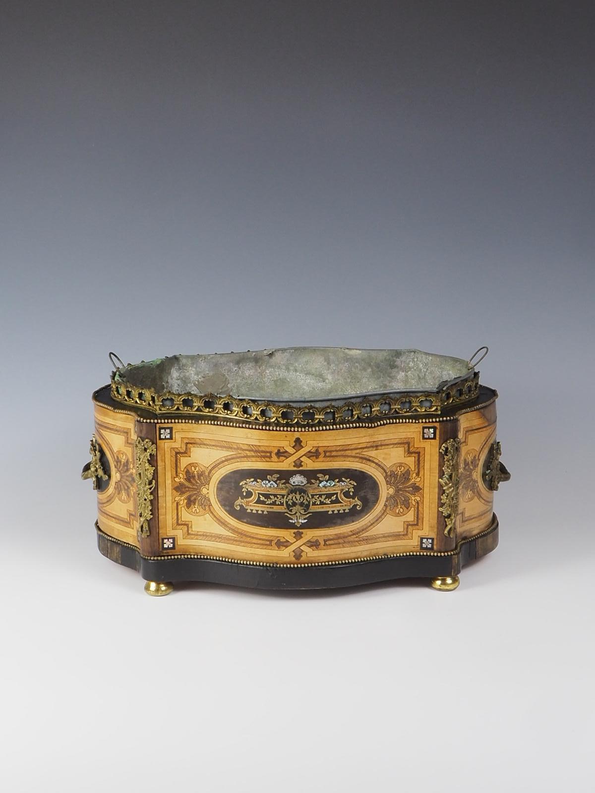 Antique Marquetry Jardiniere 19th Century French

This exquisite jardiniere hails from 19th Century France. It showcases meticulous marquetry inlay, featuring fine metals and lacquer. The piece is adorned with intricate ormolu mounts and handles,
