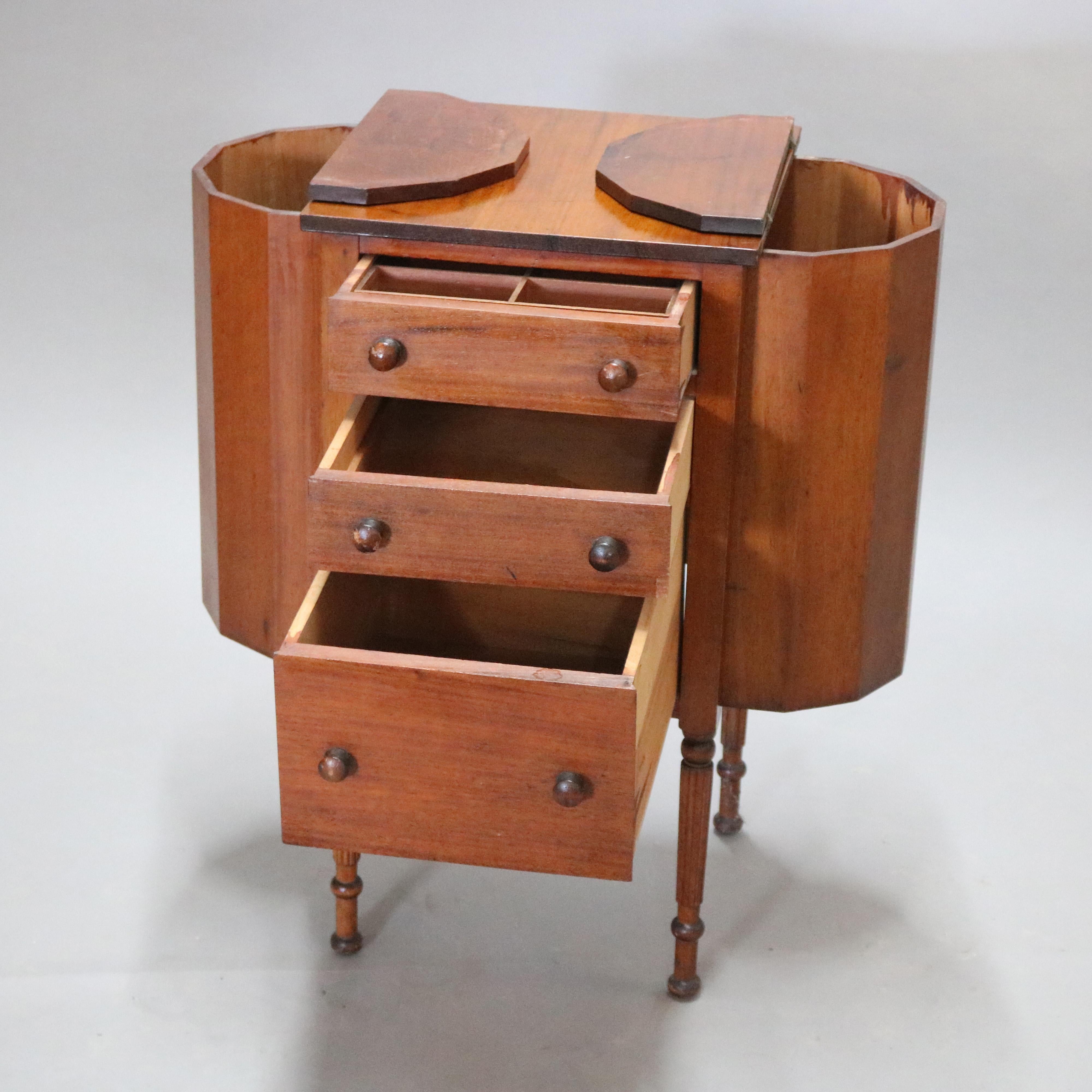 An antique Martha Washington sewing stand or cabinet offers mahogany construction with 
central tower having graduated drawers and flanked by faceted demilune project pockets, raised on turned legs, circa 1930

Measures - 28.75