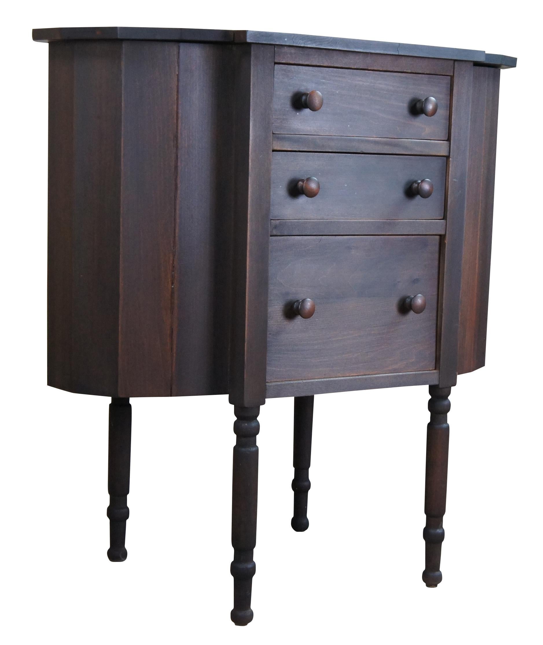 Antique Martha Washington style wooden sewing cabinet with two flip top end sections, three drawers, and turned spindle legs.
 