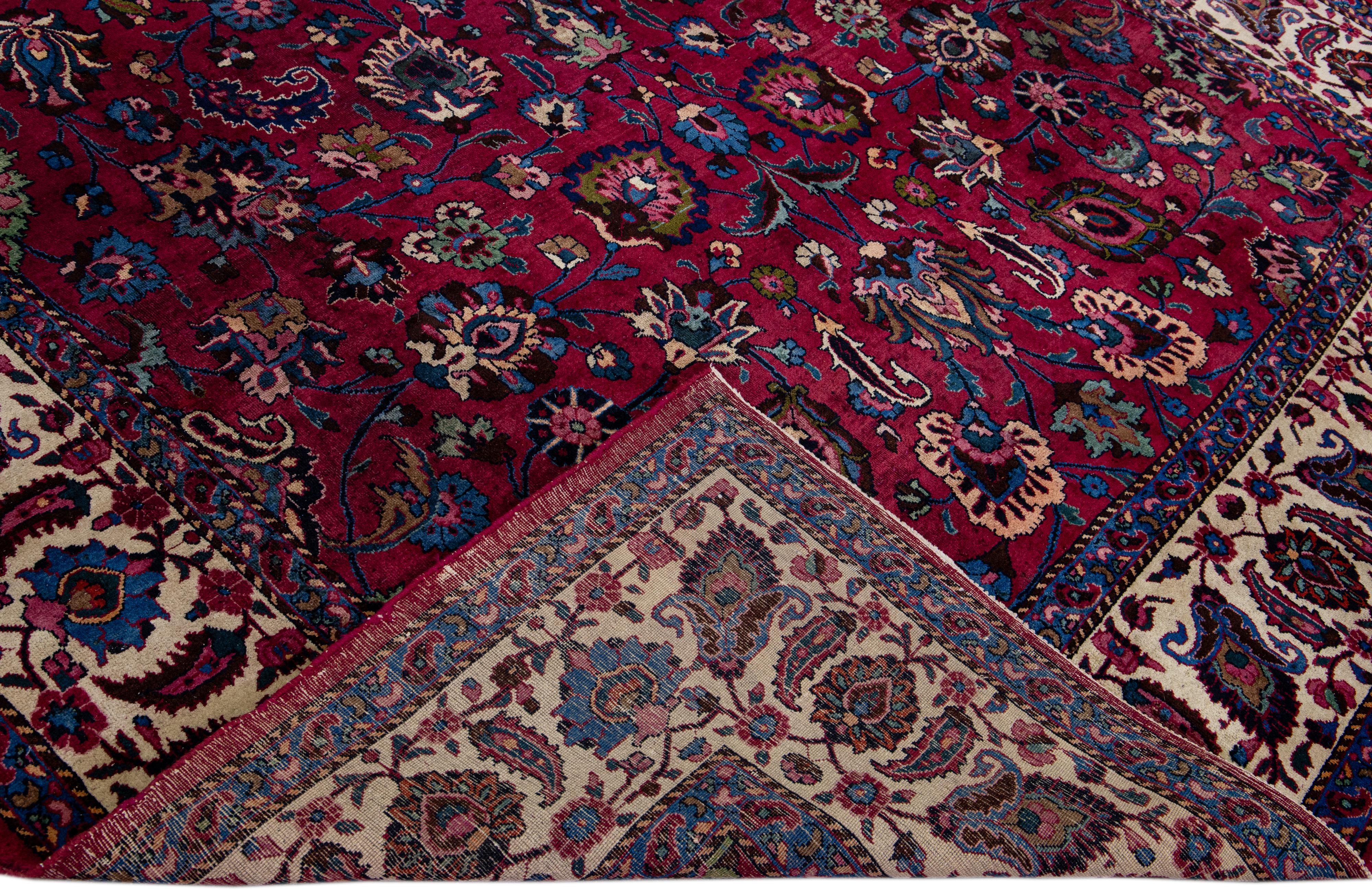 Magnifique tapis ancien de Mashad en laine nouée à la main avec le champ rouge. Ce tapis est doté d'un cadre beige et d'un magnifique motif floral classique sur toute sa surface. 

Ce tapis mesure 8'6