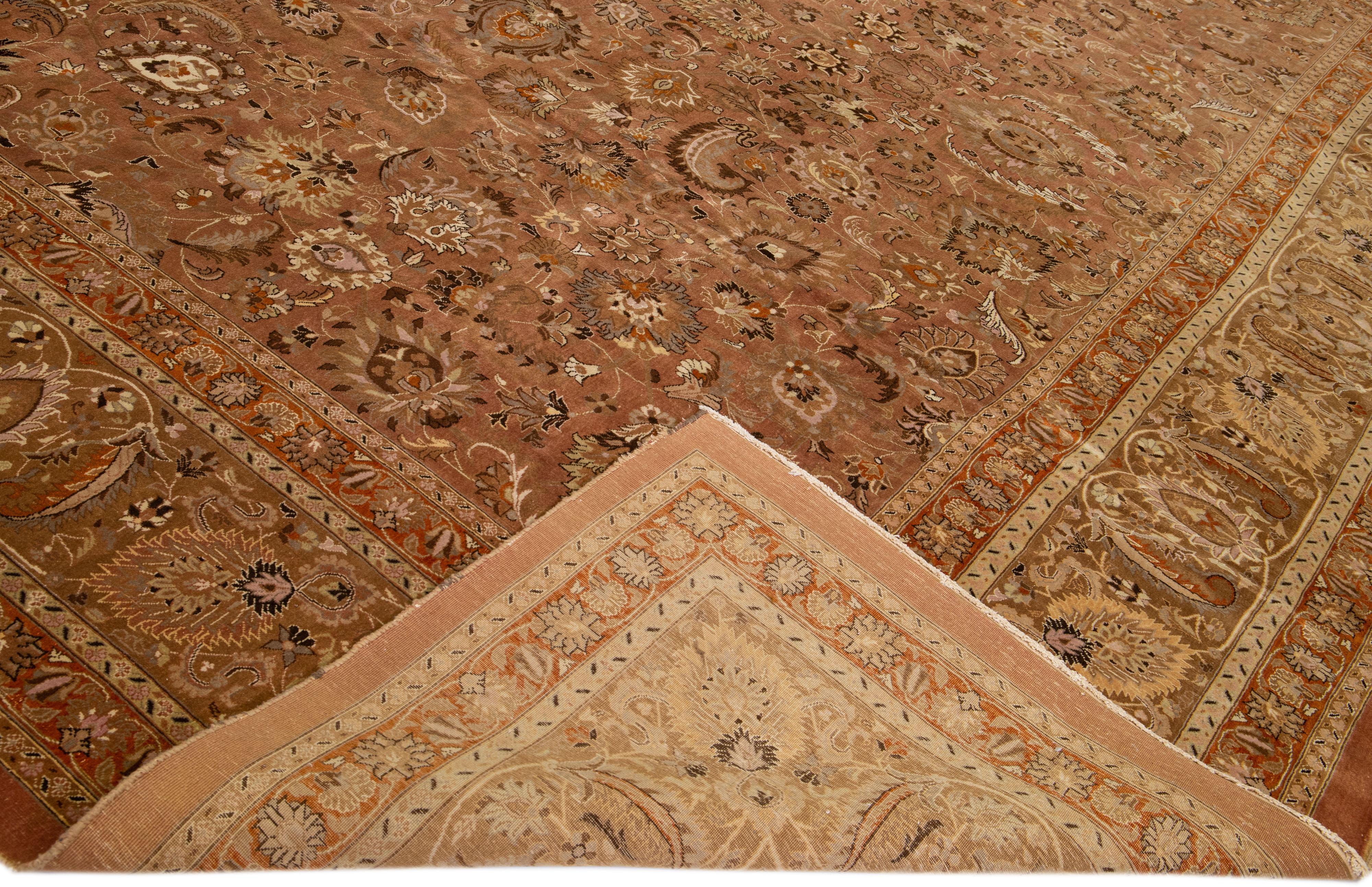 Beautiful Antique Mashad hand-knotted wool rug with a rust field. This piece rug has a brown frame in a gorgeous all-over classic floral pattern design. 

This rug measures: 16' x 23'1