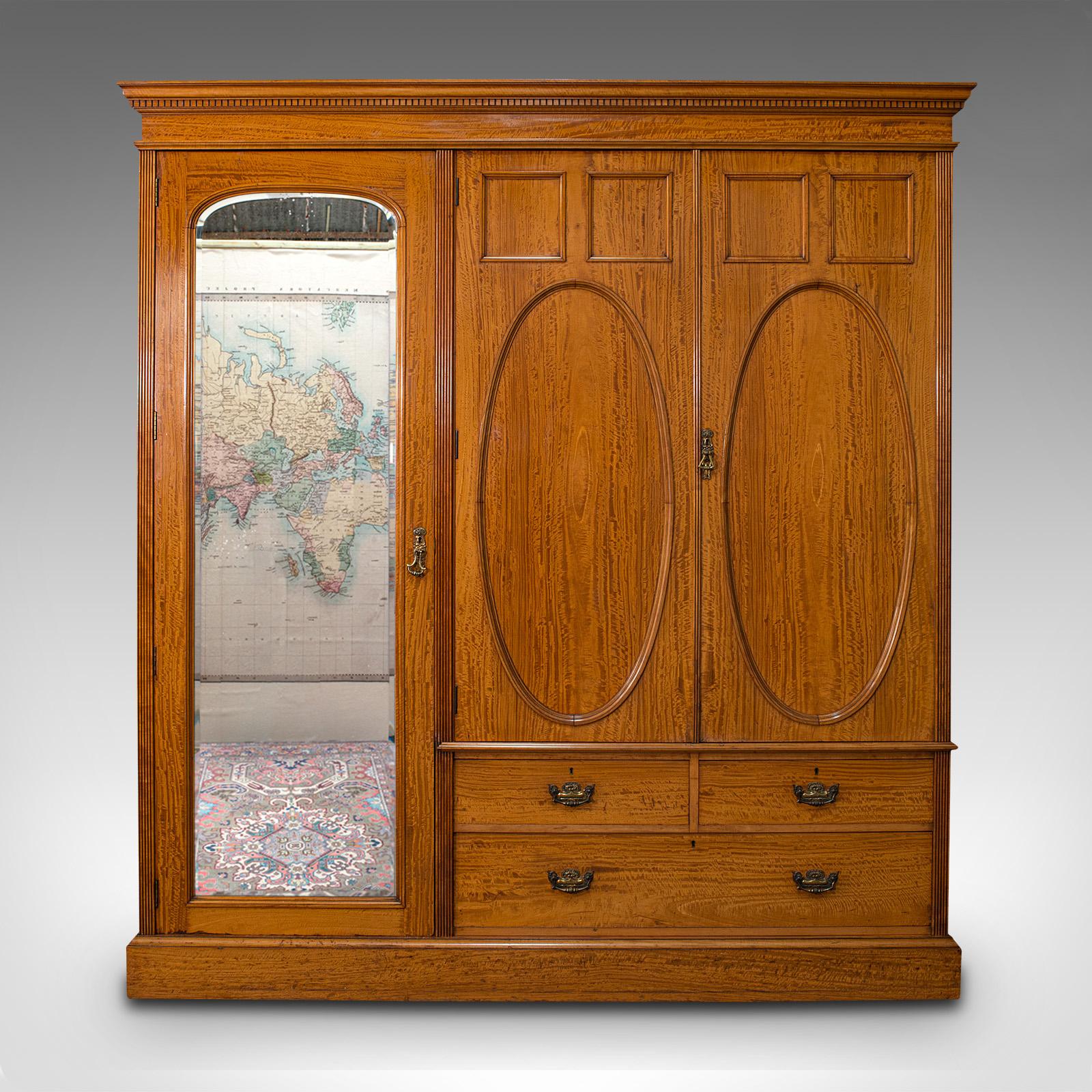 This is an antique master bedroom wardrobe. An English, satinwood over walnut linen press cupboard with dressing mirror by Maple & Co, dating to the Edwardian period, circa 1910.

Exquisite Edwardian craftsmanship as to be expected of Maple & Co,