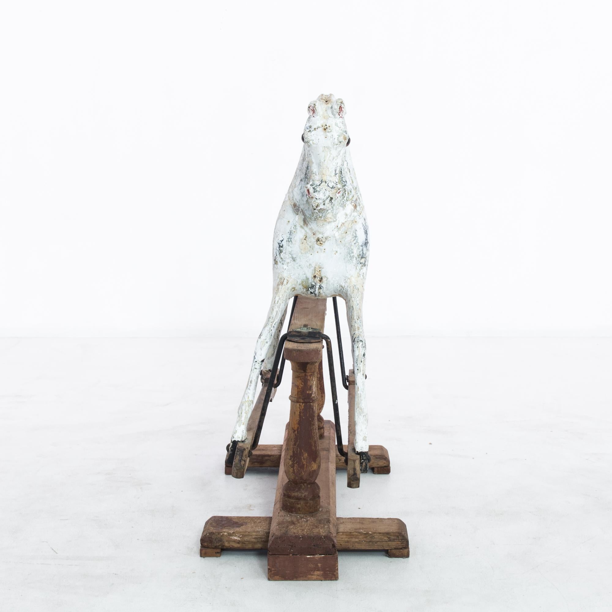 This wooden horse was made in France, circa 1900. It is fixed to a safety stand, a supportive frame that was popular in the nineteenth and early twentieth centuries for its stability. The horse features a beautifully distressed white patina, which