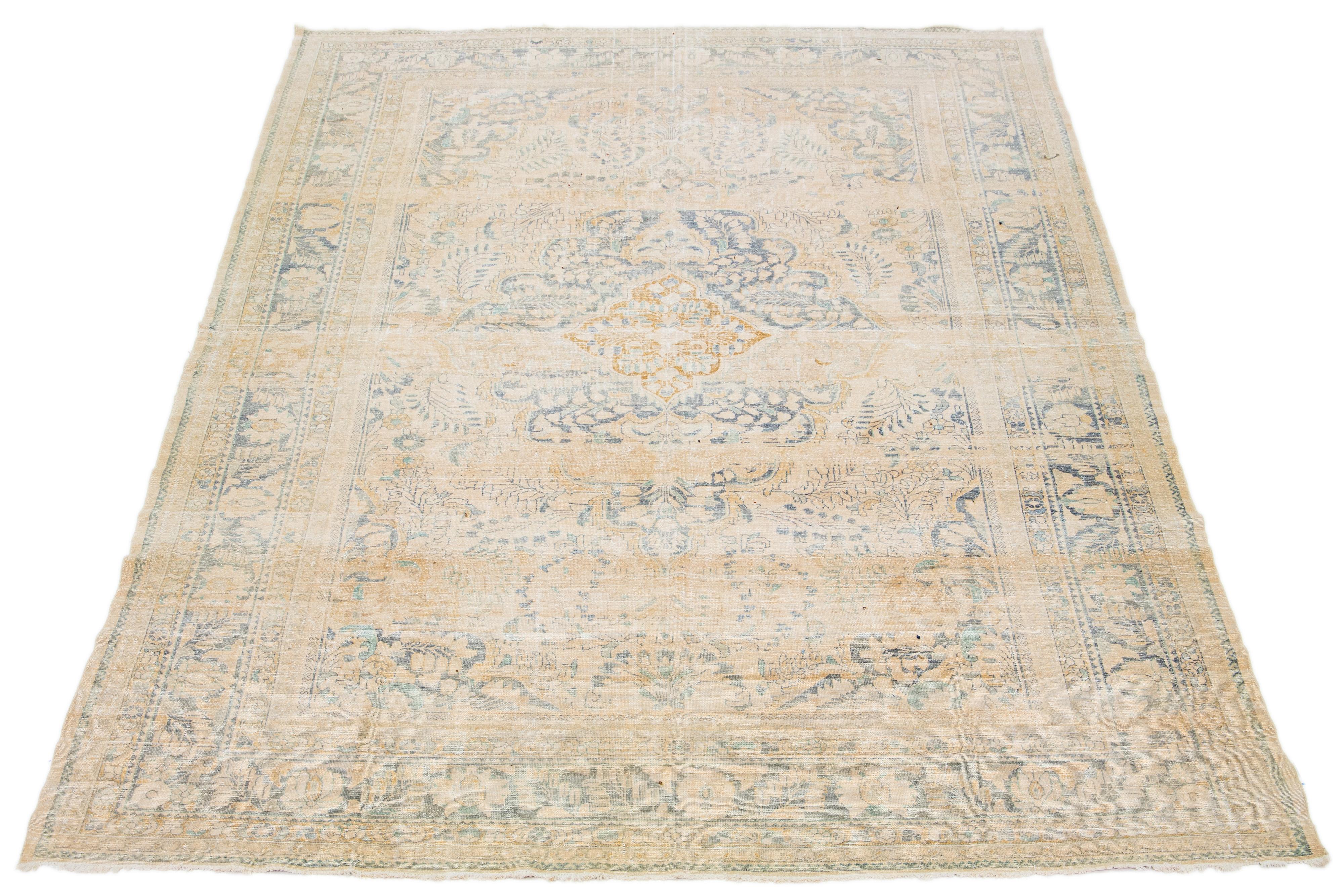 Beautiful room-size antique Malayer hand-knotted wool rug with a beige color field. This Persian rug has a gorgeous medallion design with blue accents.

This rug measures 10'4