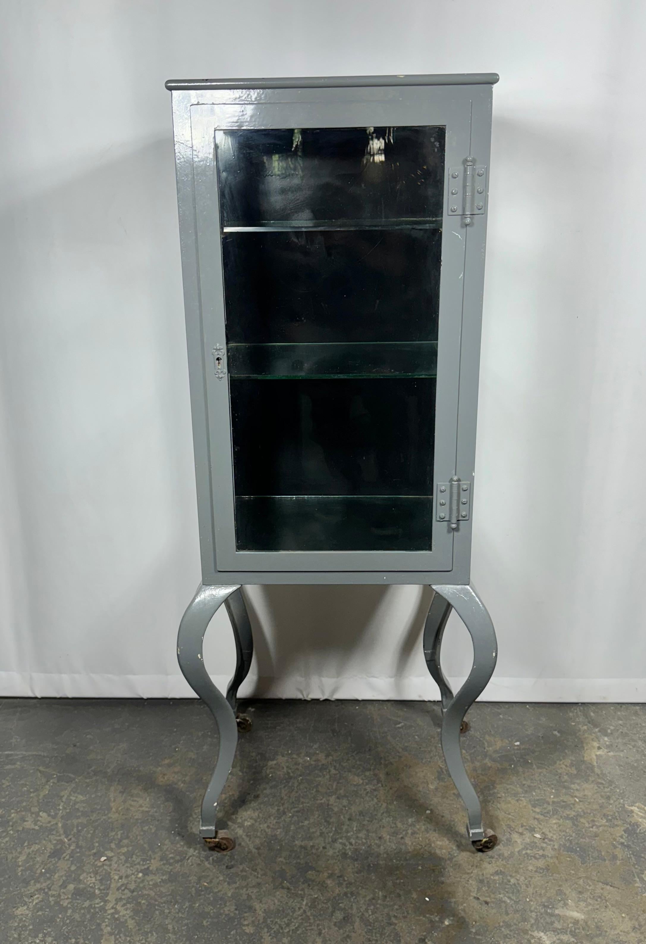 Une superbe armoire médicale avec un bel âge et des pieds CABRIOLE courbes et sexy. Peut contenir jusqu'à trois étagères. Parfait pour une salle de bain ou un bar, dOOR conserve la serrure d'origine, mais malheureusement, il n'est pas possible de