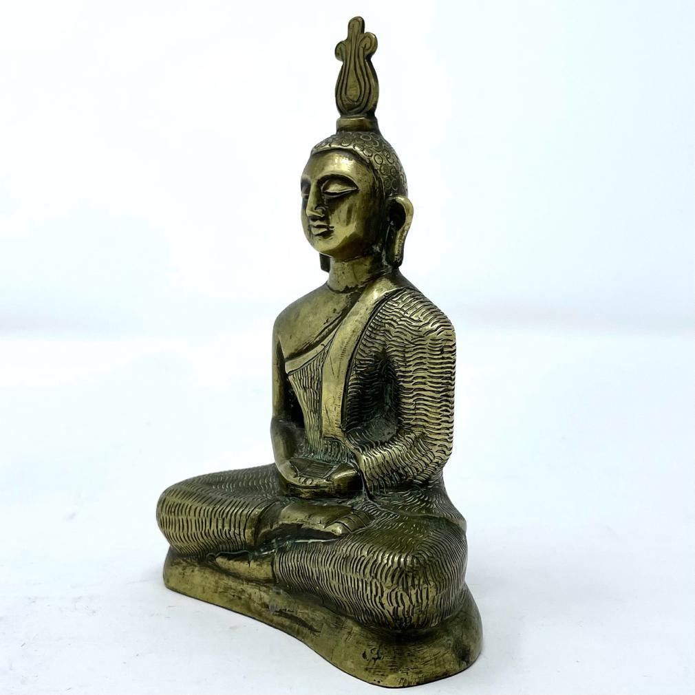 Antique Meditation Buddha, Sri Lanka, early 20th century. The seated figure cast of brass with further worked details depicting the texture of the garment, hair curls and the signature flat flame on top of the head of Sri Lankan Buddhist imagery.