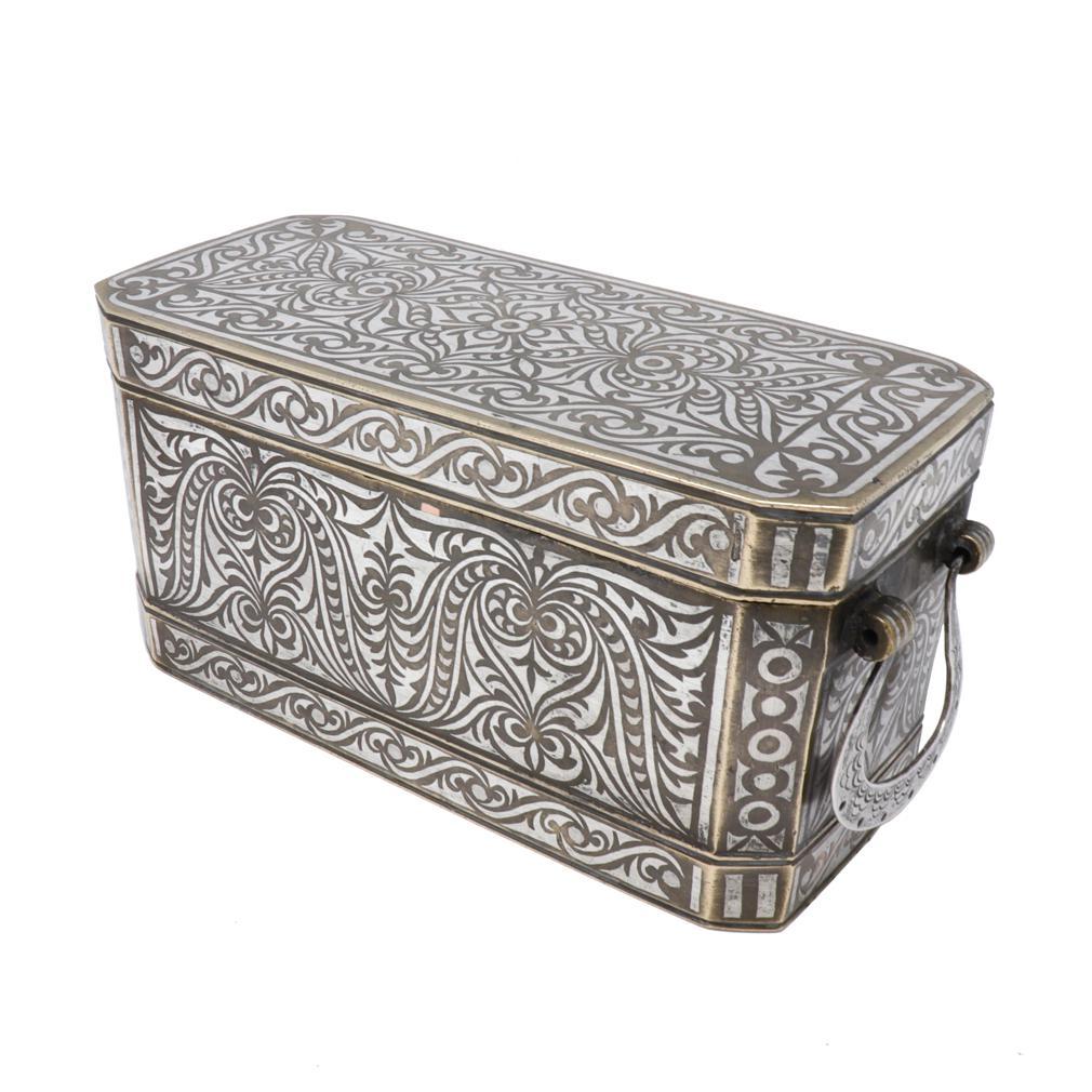 Medium Maranao Betel Nut Box, Southern Philippines (Mindanao).
A bronze box with bordered silver inlay design overall of a symmetrical floral tendril vine pattern referred to as the “okir” pattern,  a traditional design vocabulary for the Maranao
