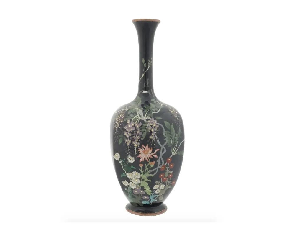 An impressive Japanese vase skillfully enameled with multicolored floral composition depicting wisteria, chrysanthemums and other flowers and a flying bird. Meiji era, 1868 to 1912. Unmarked. Antique Japanese Metalware And Oriental Decorative