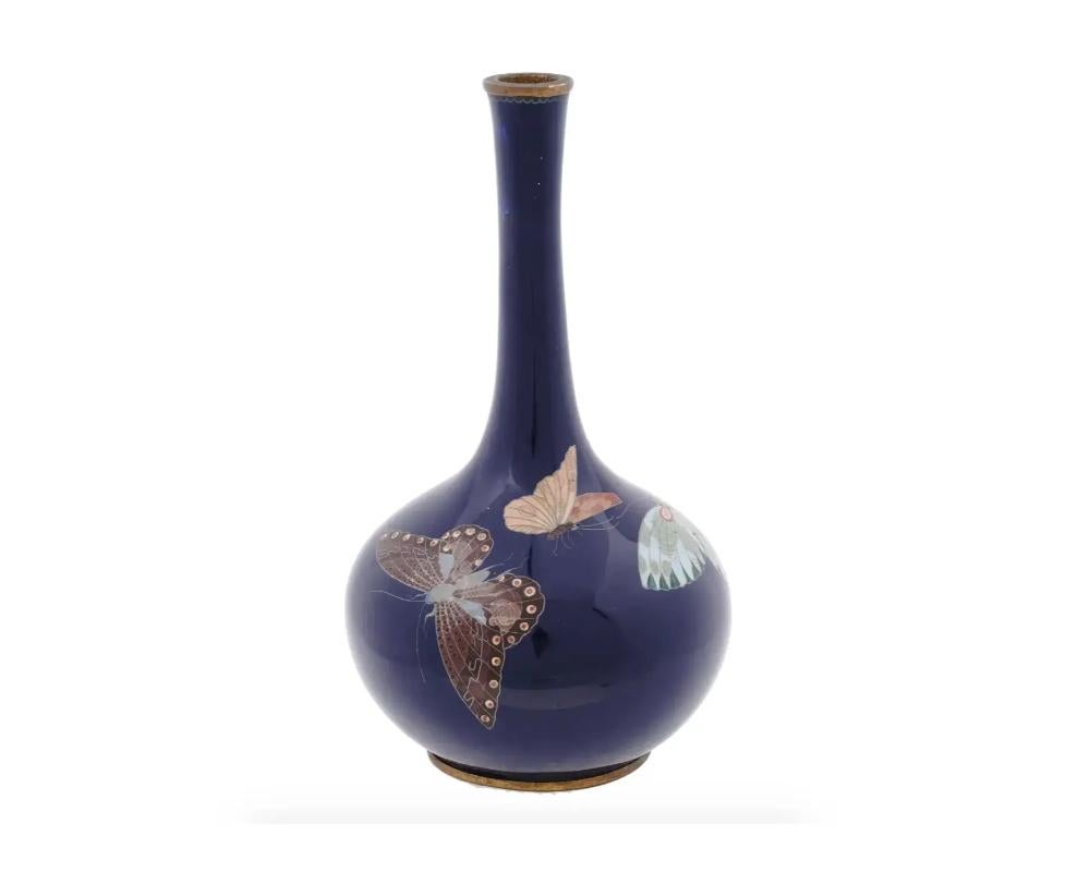 Eine hochwertige japanische Knospenvase aus dem späten 19. Jahrhundert mit einem kugelförmigen Körper und einem hohen, umgedrehten Hals. Die Vase ist mit einer polychromen Darstellung von Schmetterlingen in Cloisonné-Technik auf kobaltblauem Grund