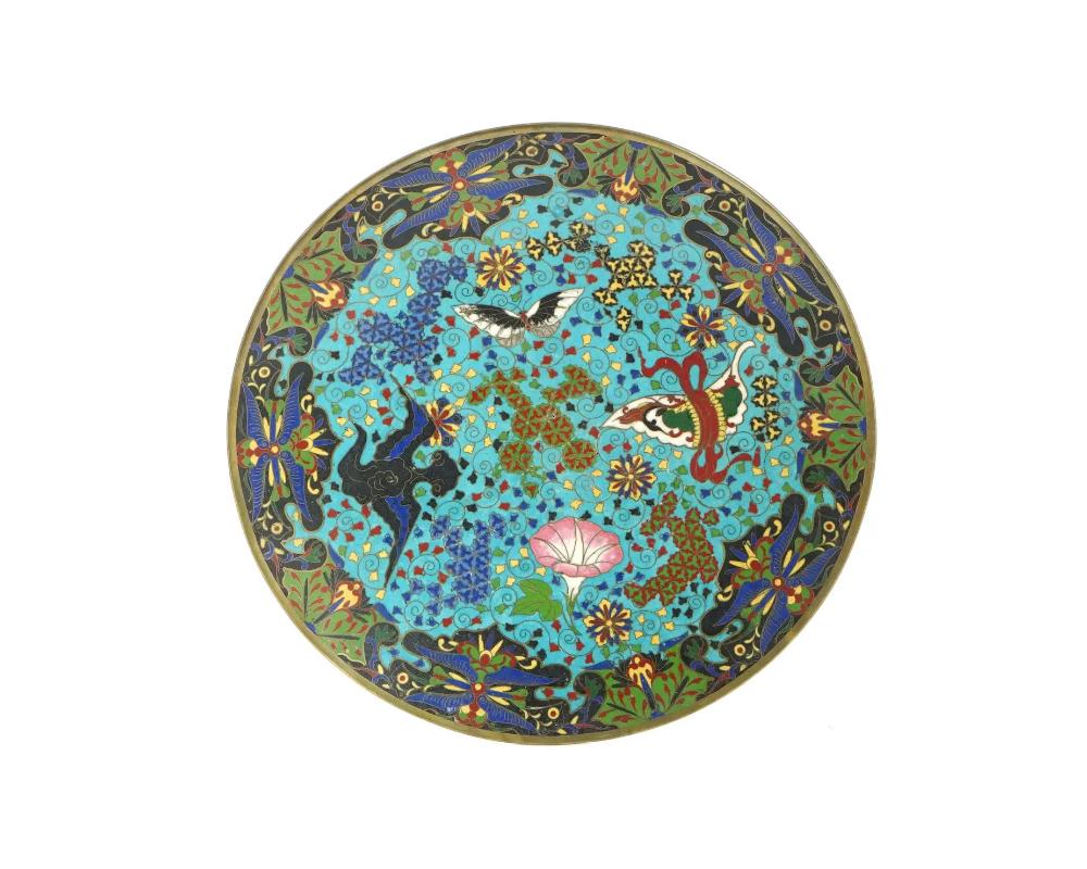 Ancienne assiette ou chargeur en émail japonais de l'ère Meiji. L'intérieur de l'assiette est orné d'une image en émail polychrome d'un papillon, de fleurs épanouies entourées de rinceaux traditionnels, floraux et géométriques sur le fond turquoise