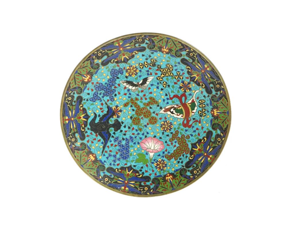 Antiguo plato o cargador esmaltado japonés de la era Meiji. El interior del plato está adornado con una imagen de esmalte policromado de una mariposa, flores en flor rodeadas de volutas foliadas tradicionales, florales y geométricas sobre fondo