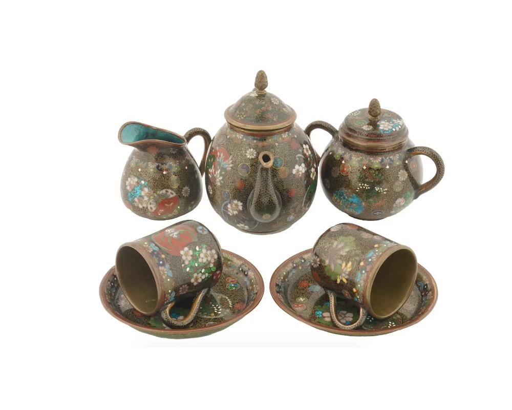 A superb antique Japanese cloisonne enamel tea set from the Meiji Era, 1868 to 1912. The set comprises 2 cups and saucers, teapot, sugar bowl and creamer decorated with fine enamels depicting butterflies, floral arrangements and tendrils in gilded