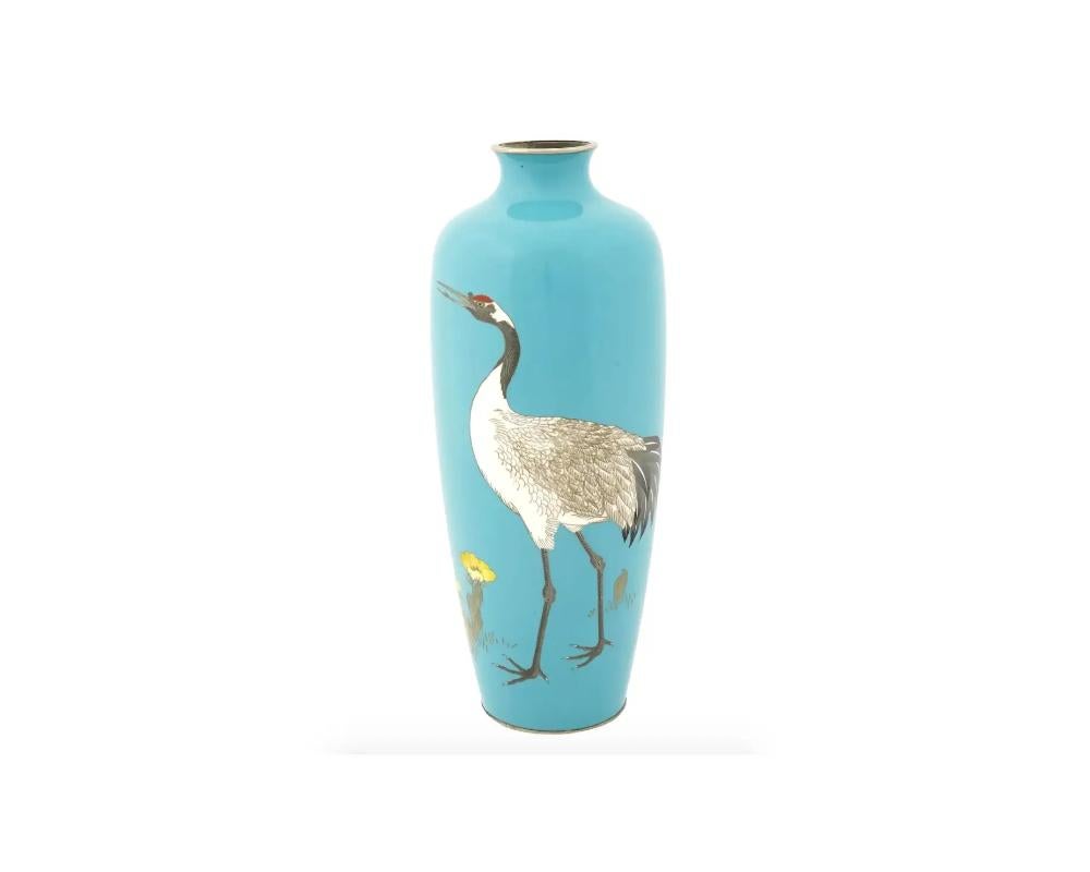 A fine antique Japanese enamel brass vase featuring an elongated body with rounded shoulders and wide short neck. The surface is skillfully decorated with a polychrome cloisonne enamel image of a red-crowned crane walking among blooming yellow