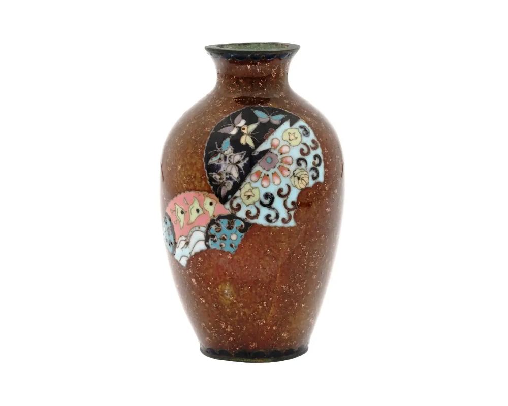 A miniature antique Japanese Meiji Era brass and enamel vase. Circa: early 20th century. The baluster form vase is enameled with polychrome images of fans and a butterfly made in the Cloisonne technique. The ware is inlaid with Gold stones.