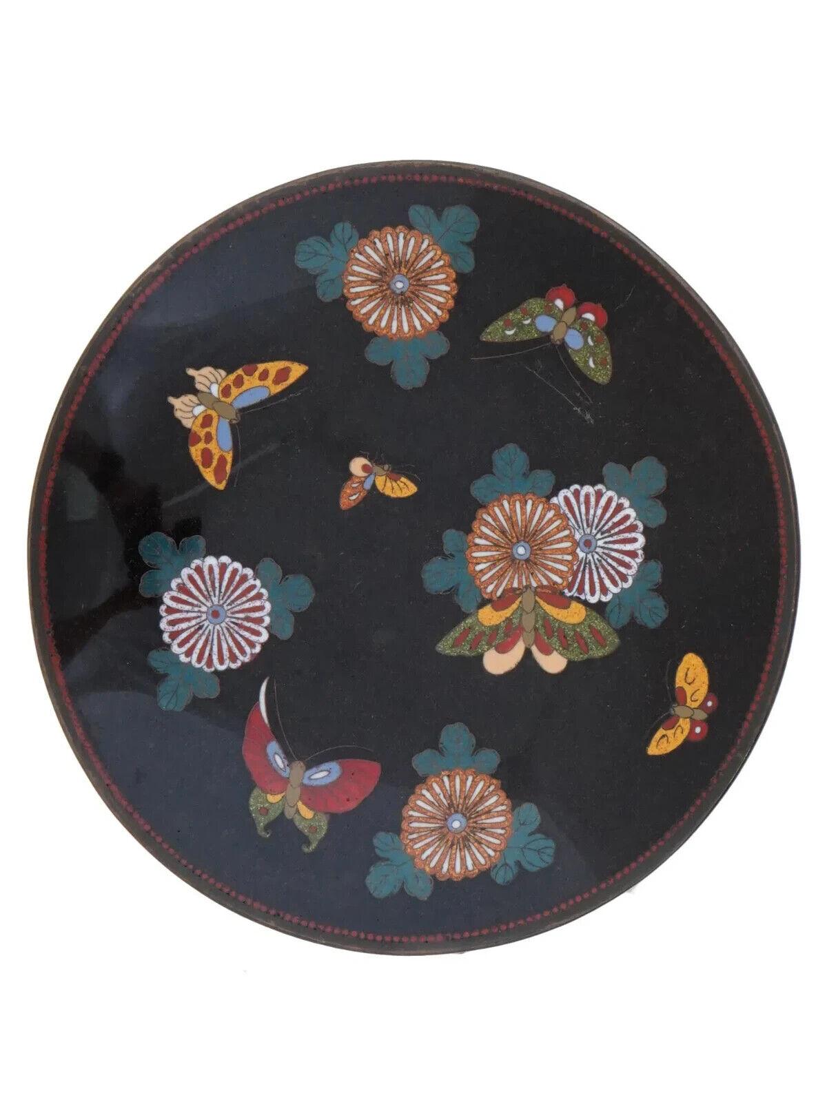 Antiguo plato japonés de cobre con diseño de esmalte cloisonné policromado. Periodo Meiji, de 1868 a 1912. Motivo de mariposas y flores sobre fondo negro. Hay una suspensión en la parte trasera. Decoración oriental de colección para