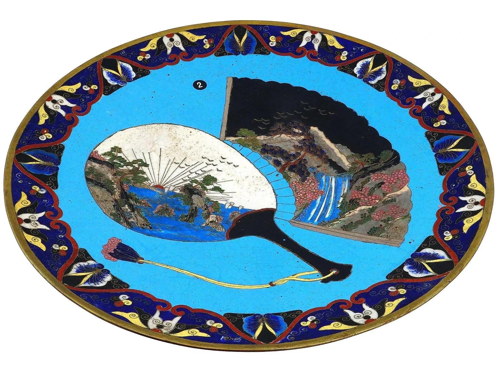 Une assiette émaillée japonaise ancienne de l'ère Meiji très décorative. La partie centrale de l'assiette est émaillée d'un design polychrome avec des images de deux éventails ornés de paysages traditionnels. Entouré d'une bordure de motifs floraux