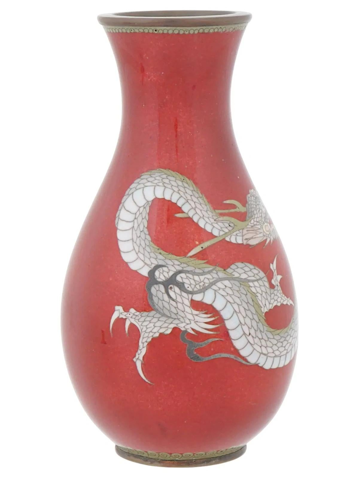 Eine japanische Emaille-Vase. Die Vase hat einen kugelförmigen Körper mit einem breiten Hals und einer geriffelten Öffnung. Die Außenseite des Geschirrs ist mit einem polychromen Emaille-Muster verziert, das einen Drachen auf rotem Grund darstellt