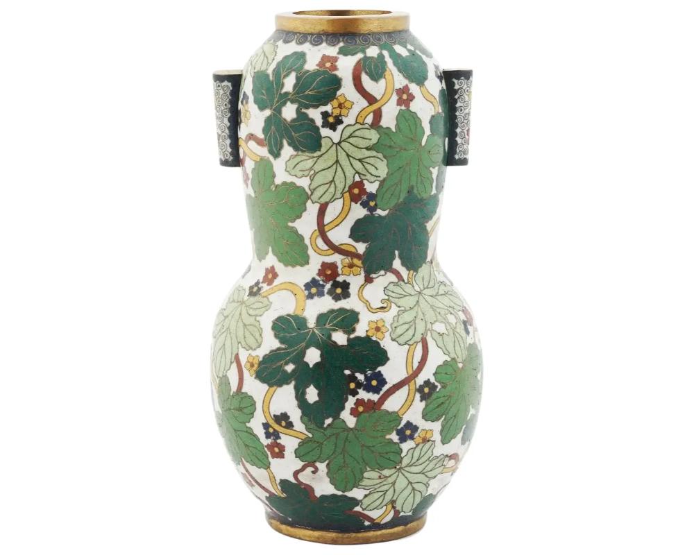 A very fine antique Japanese cloisonne covered gourd shaped vase having a white enamel ground painted with polychrome vines and flowers. Featuring two cylindrical handles also decorated with cloisonne enamel designs. Marked to the bottom. Meiji era,
