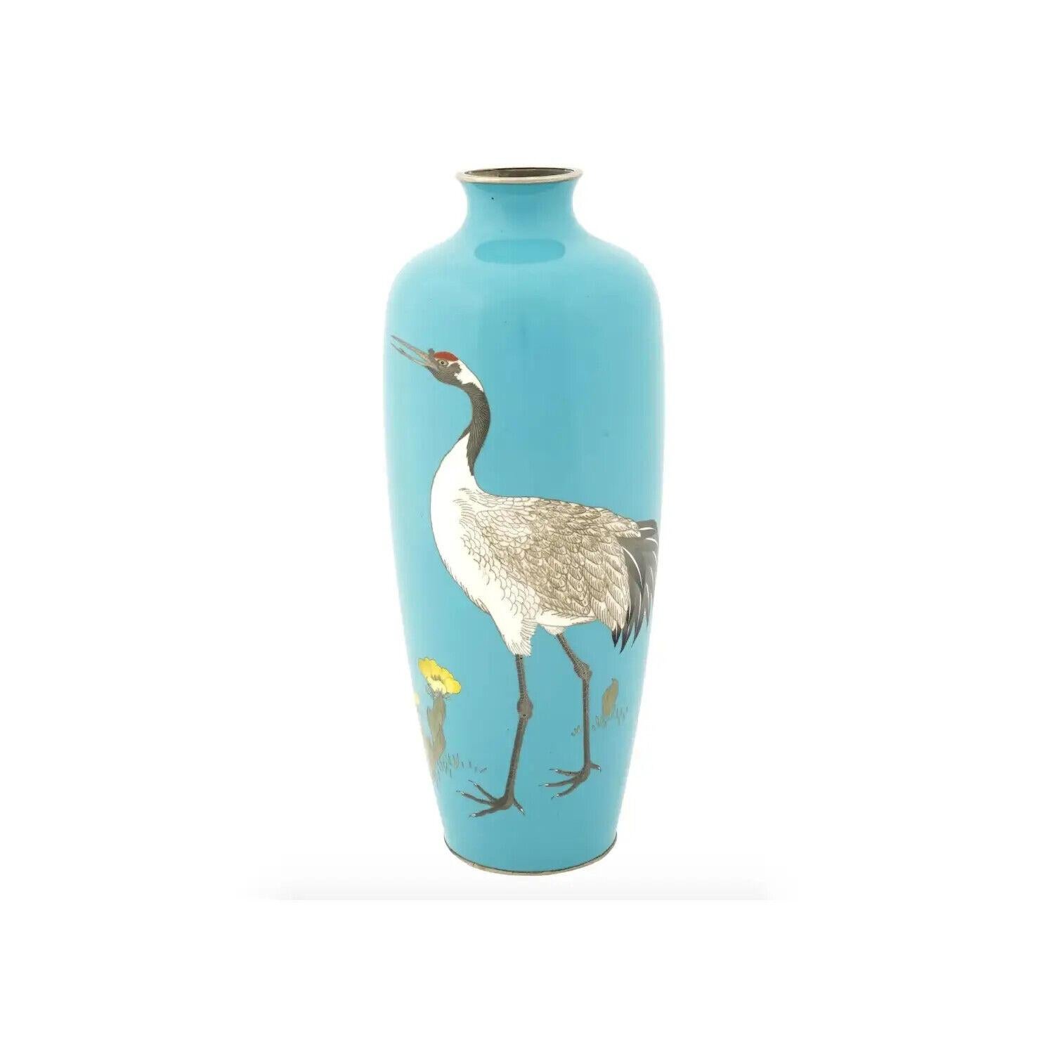 A fine antique Japanese enamel brass vase featuring an elongated body with rounded shoulders and wide short neck. The surface is skillfully decorated with a polychrome cloisonne enamel image of a red-crowned crane walking among blooming yellow