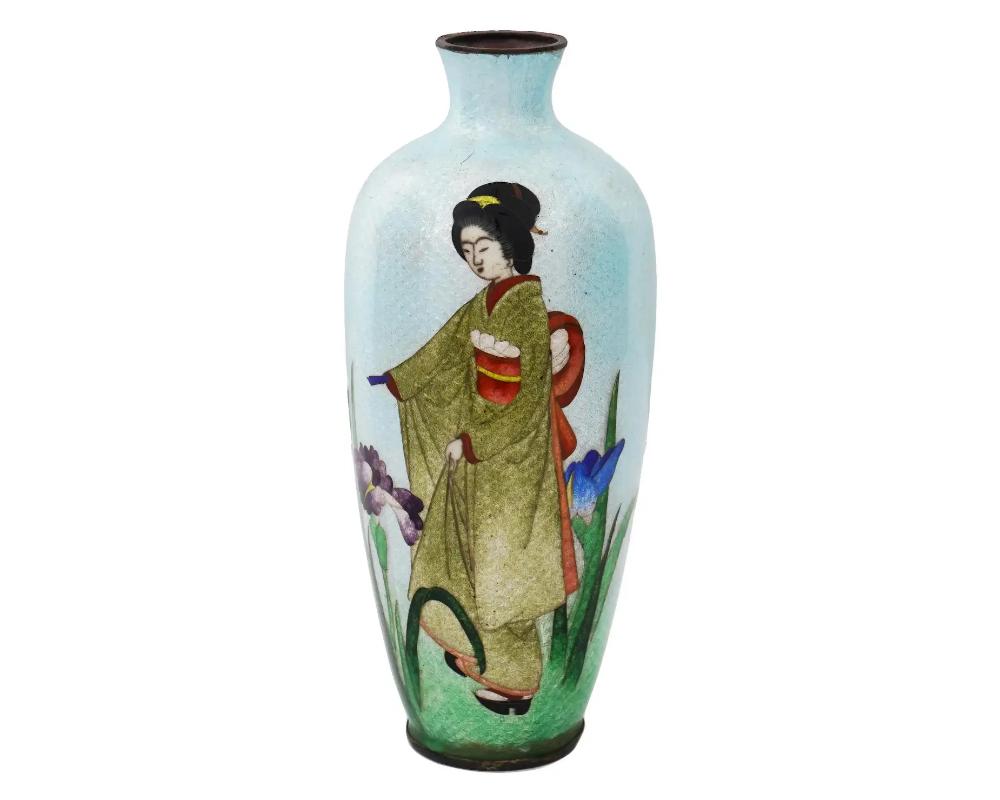 A large antique Japanese, late Meiji era, Ginbari enamel over copper vase. The urn shaped vase is enameled with a polychrome scene of a Geisha lady in a garden with blossoming flowers on the light blue and green ground made in the Ginbari Cloisonne