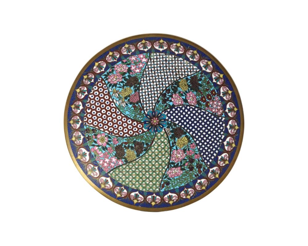 Plaque décorative japonaise ancienne de l'ère Meiji en émail sur cuivre. La plaque est réalisée dans un motif de panneau tourbillonnant. Les panneaux sont ornés d'images polychromes de fleurs épanouies, d'ornements réticulés et géométriques, et