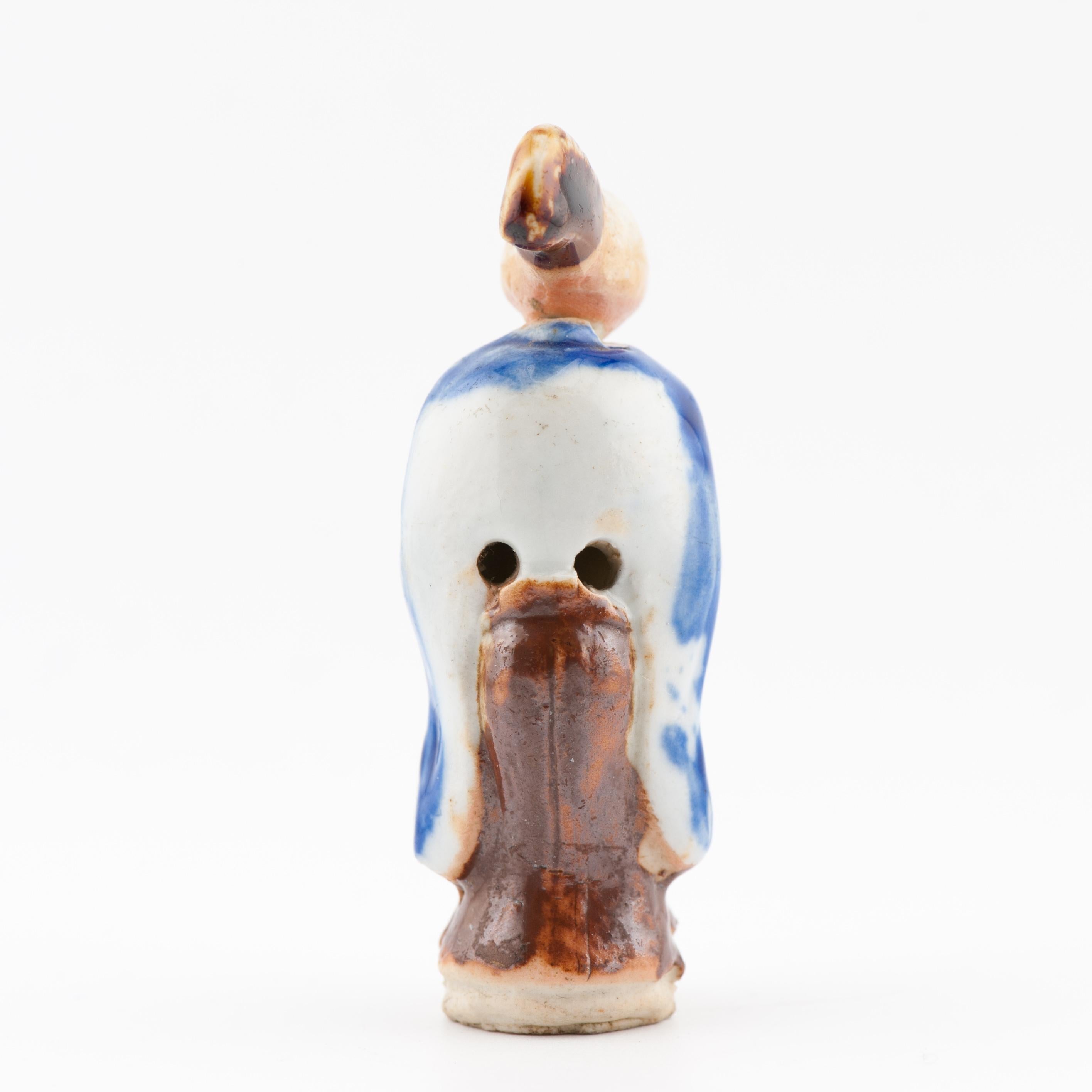 Si tratta di un antico modello di netsuke in porcellana di Hirado di fattura insolita, raffigurante una scimmia dispettosa vestita da danzatrice Sanbosa. La figura è modellata in modo nitido con smalti blu cobalto e marrone ferro applicati alla